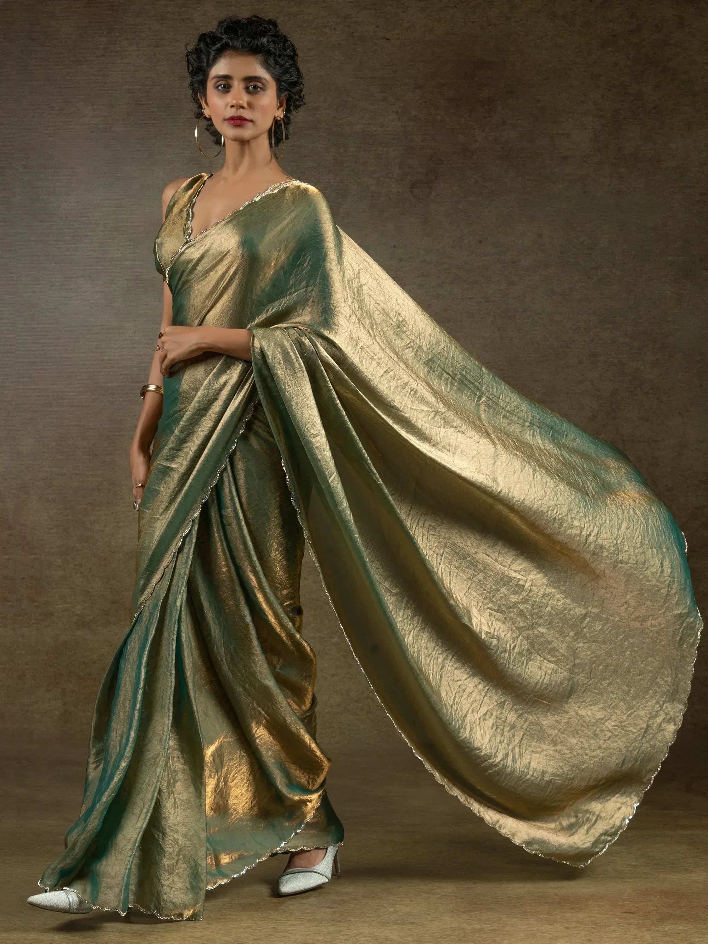 Elegant green and gold metallic saree with scalloped border, styled for Indian ethnic wear occasions.
