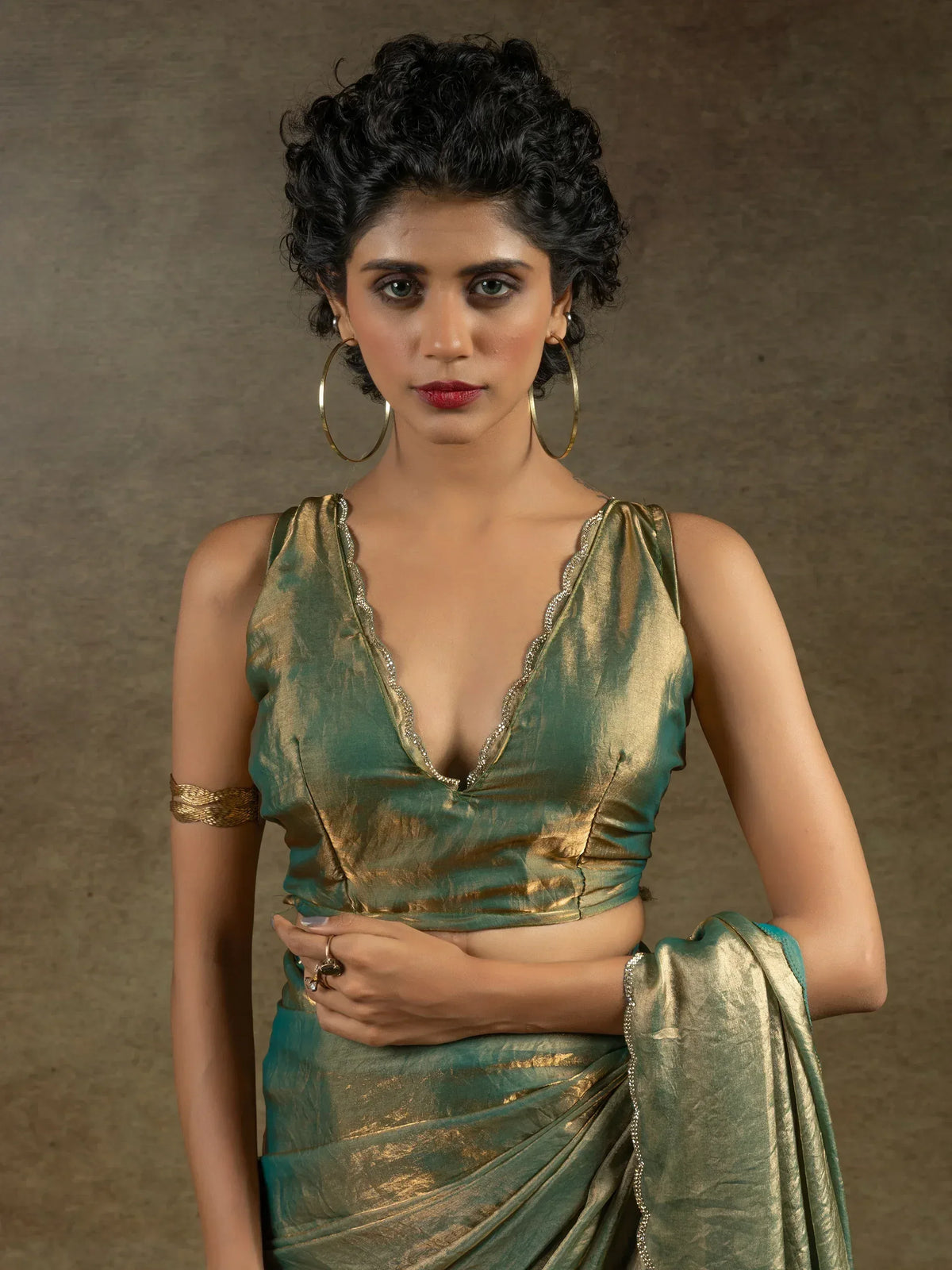 Woman in elegant green and gold saree with deep V-neck blouse, styled for Indian ethnic wear occasions.