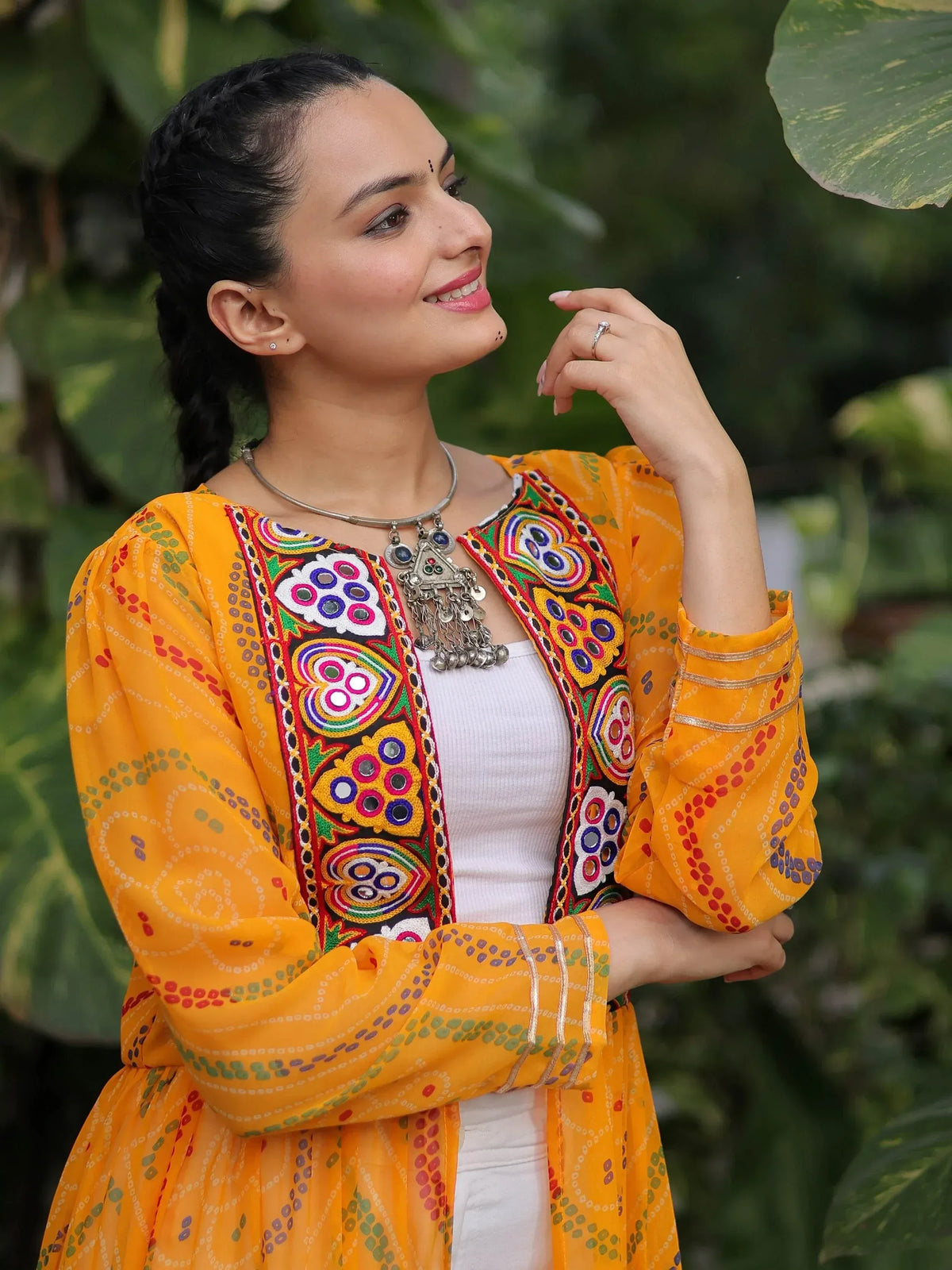 Woman in vibrant yellow embroidered ethnic kurta with mirror work, styled with silver jewelry for festive occasions.
