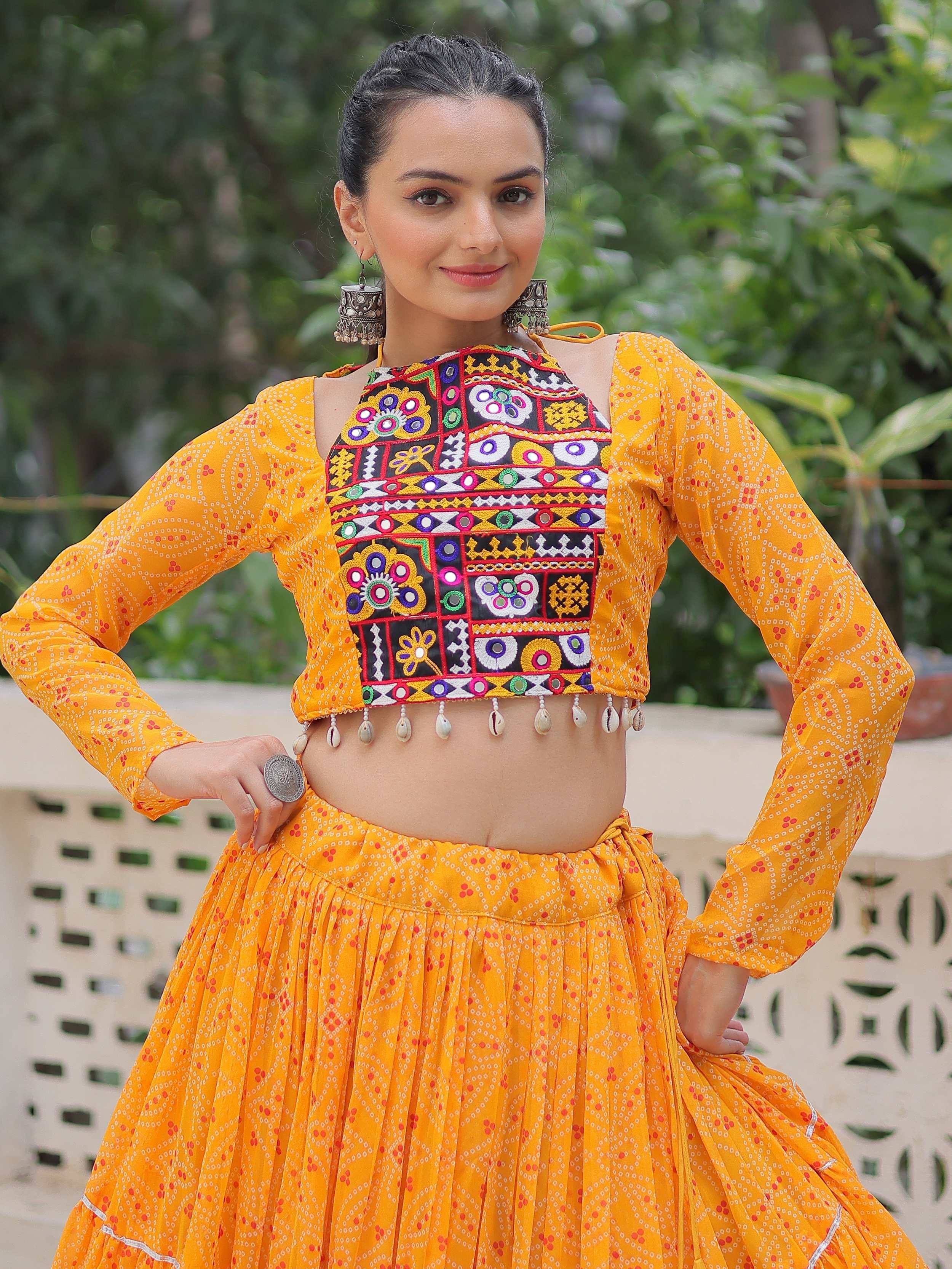 Vibrant yellow ethnic crop top with mirror work and shell tassels paired with matching skirt, perfect for festive occasions.
