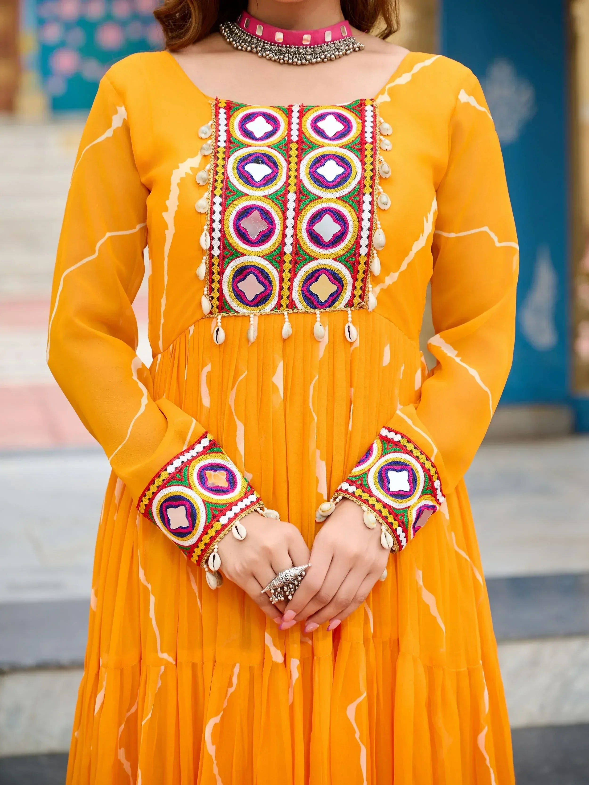 Vibrant yellow ethnic gown with colorful mirror embroidery and shell detailing, perfect for festive occasions.