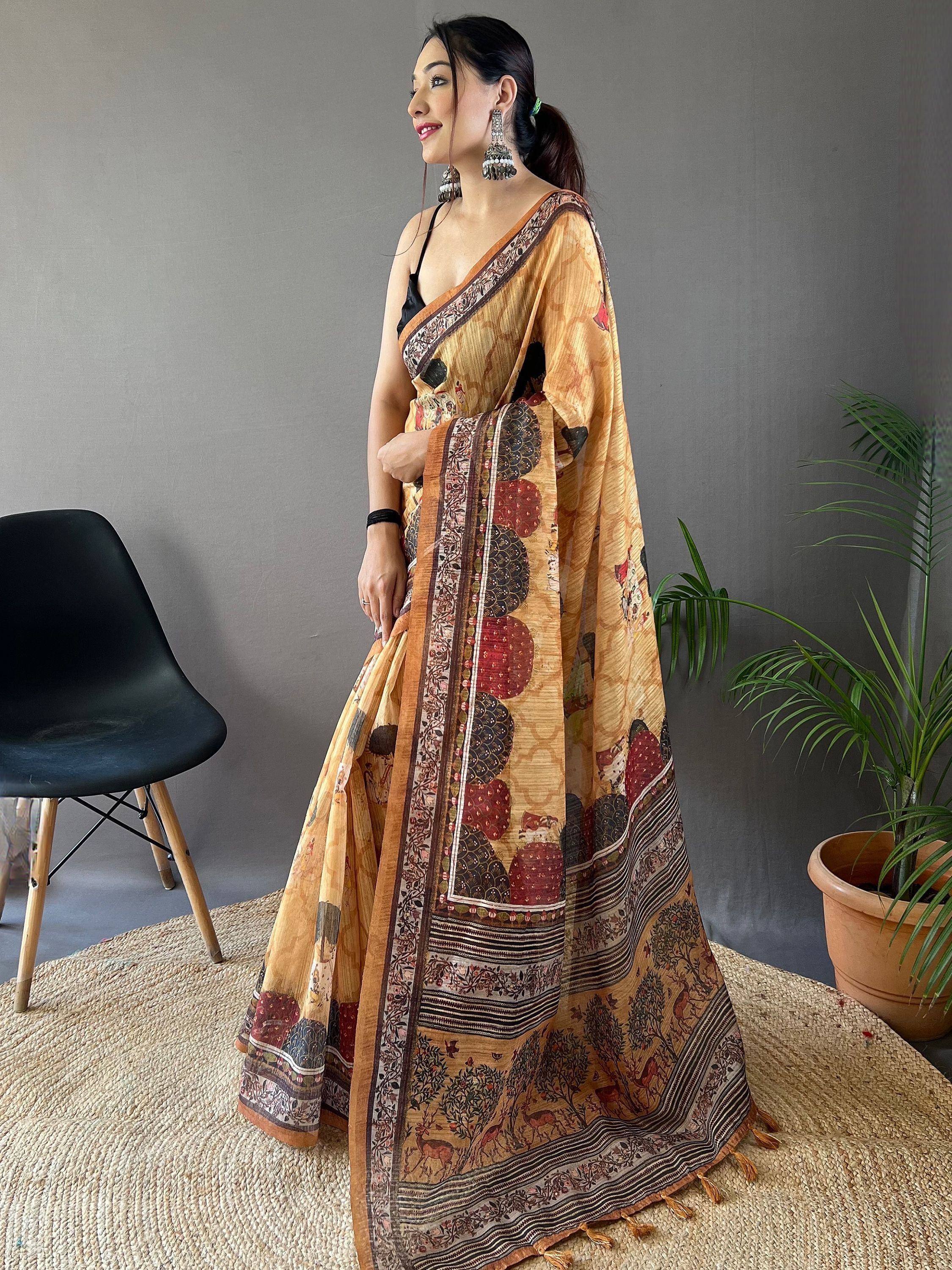 Woman in elegant Indian saree with intricate printed motifs and tassels, styled with black blouse and jhumka earrings.