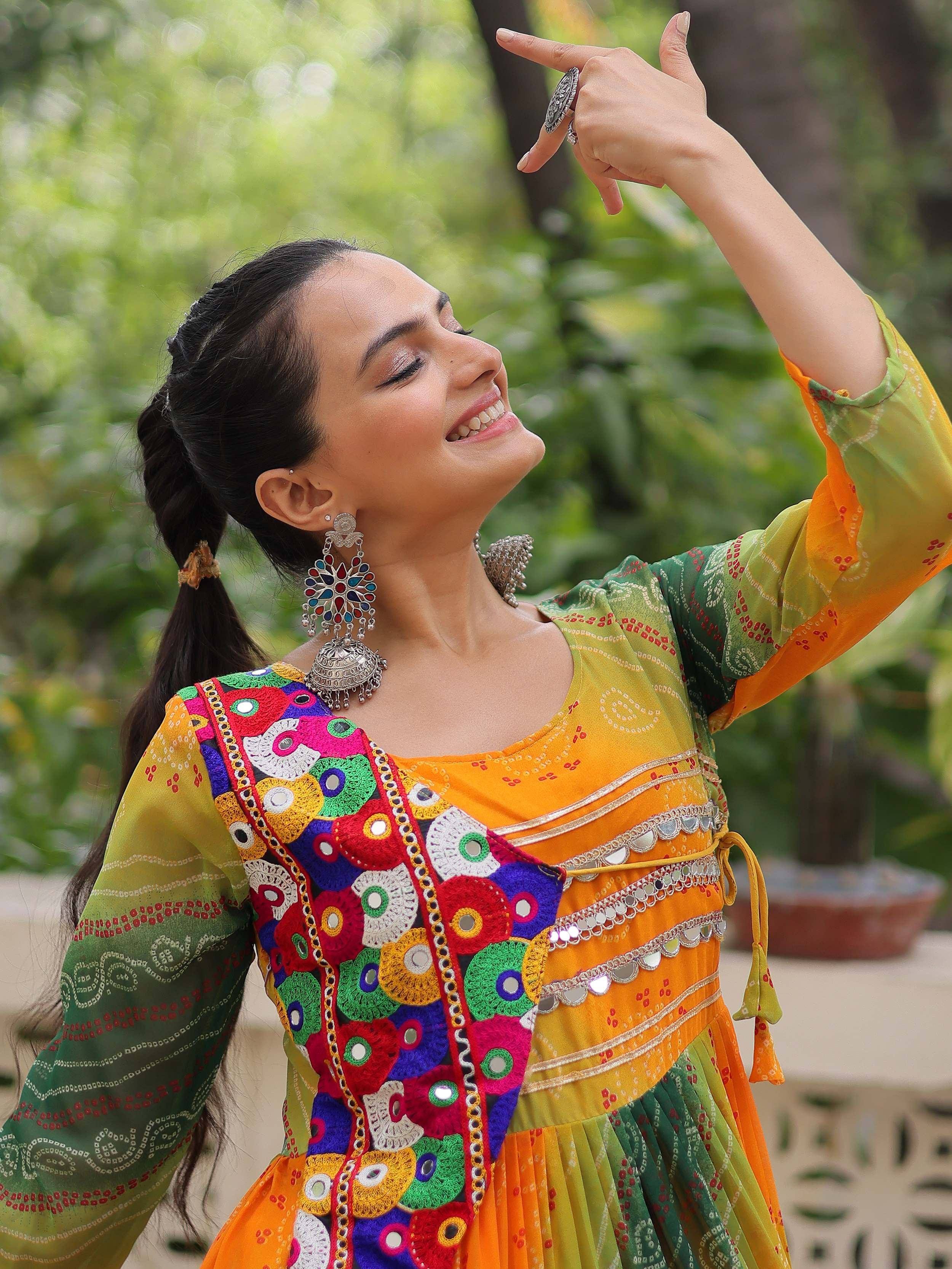 Woman in vibrant Indian ethnic wear with mirror work, colorful embroidery, and traditional jewelry, dancing outdoors.