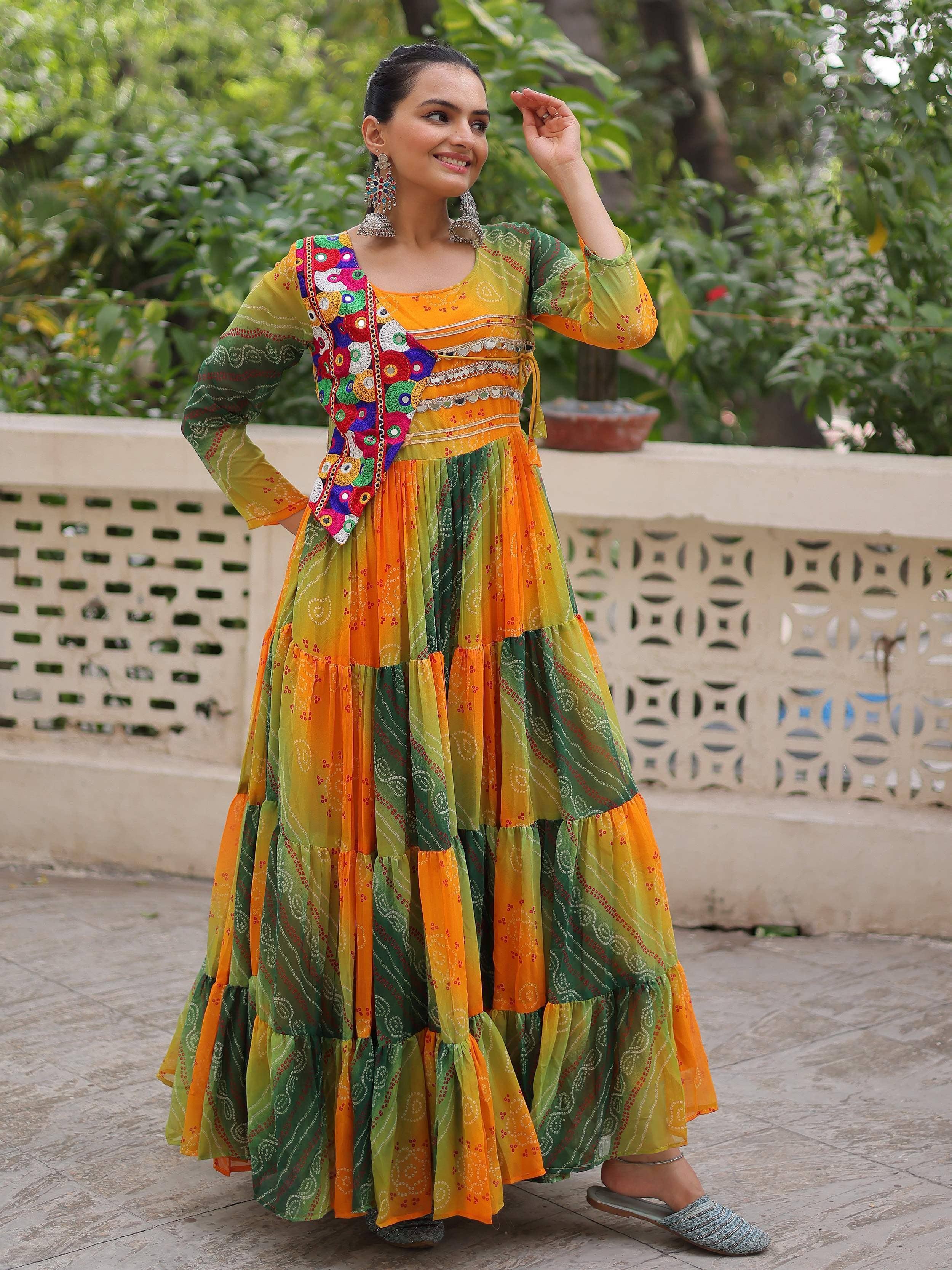 Colorful Indian ethnic gown with mirror work, tiered skirt, and vibrant green-orange print for festive occasions
