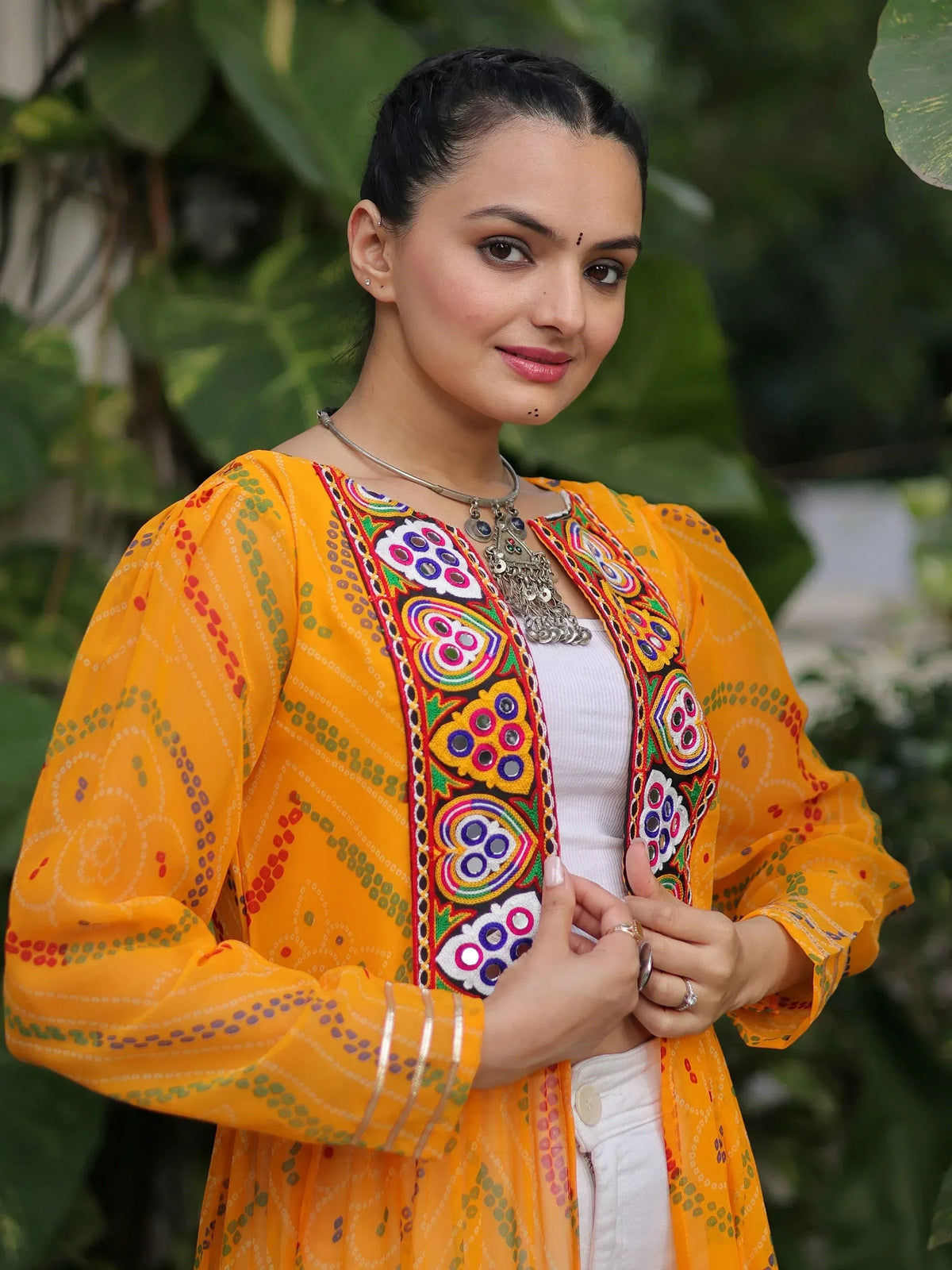 Woman in vibrant yellow ethnic kurta with mirror embroidery, styled with silver jewelry for festive occasions