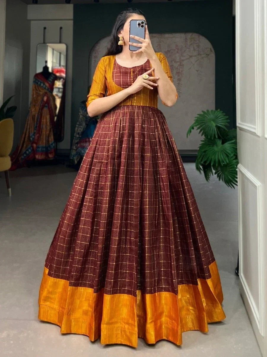 Woman in a checked maroon and mustard yellow ethnic gown posing indoors