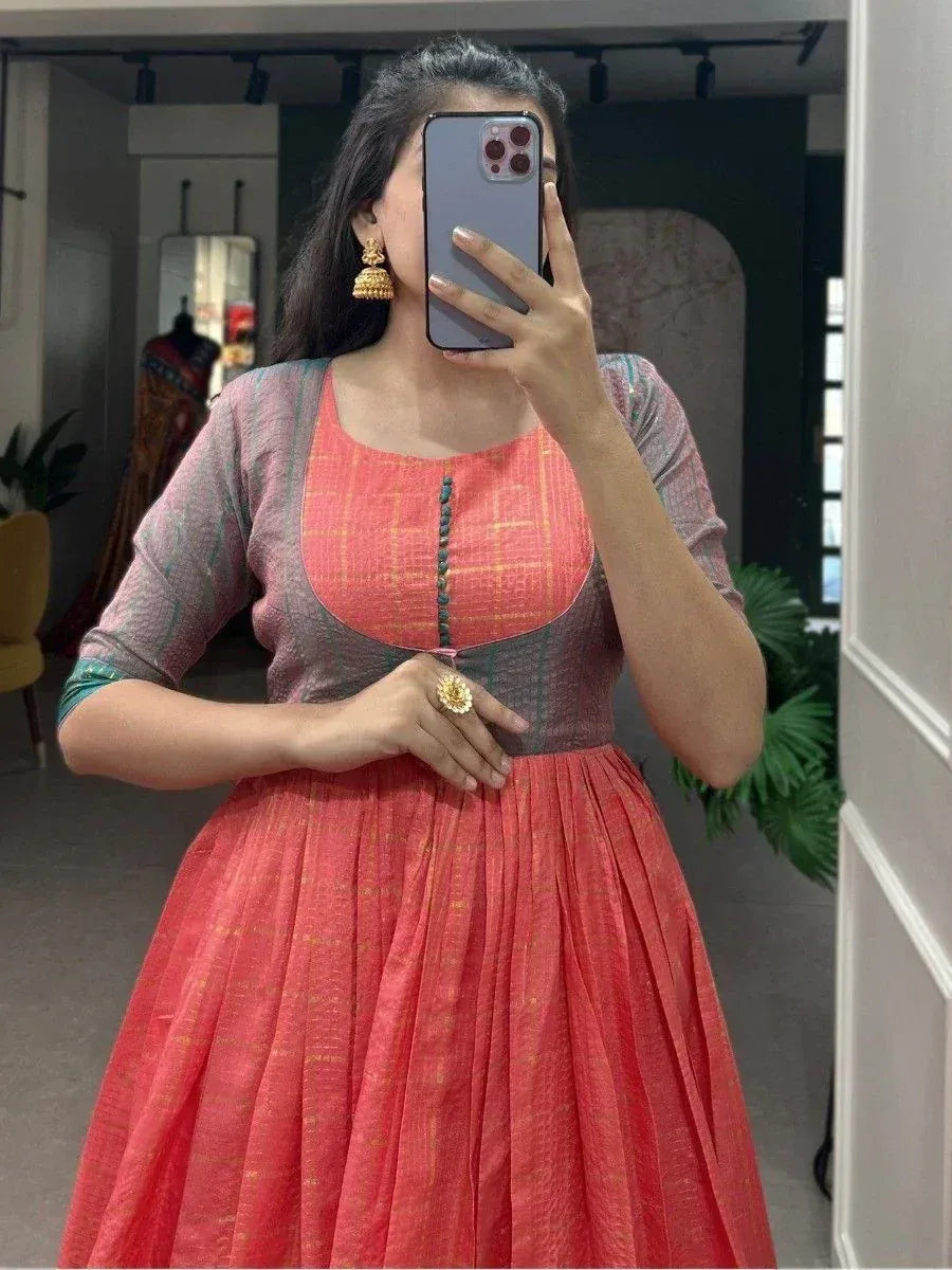 Woman wearing coral ethnic gown with checkered bodice, gold jhumka earrings, mirror selfie