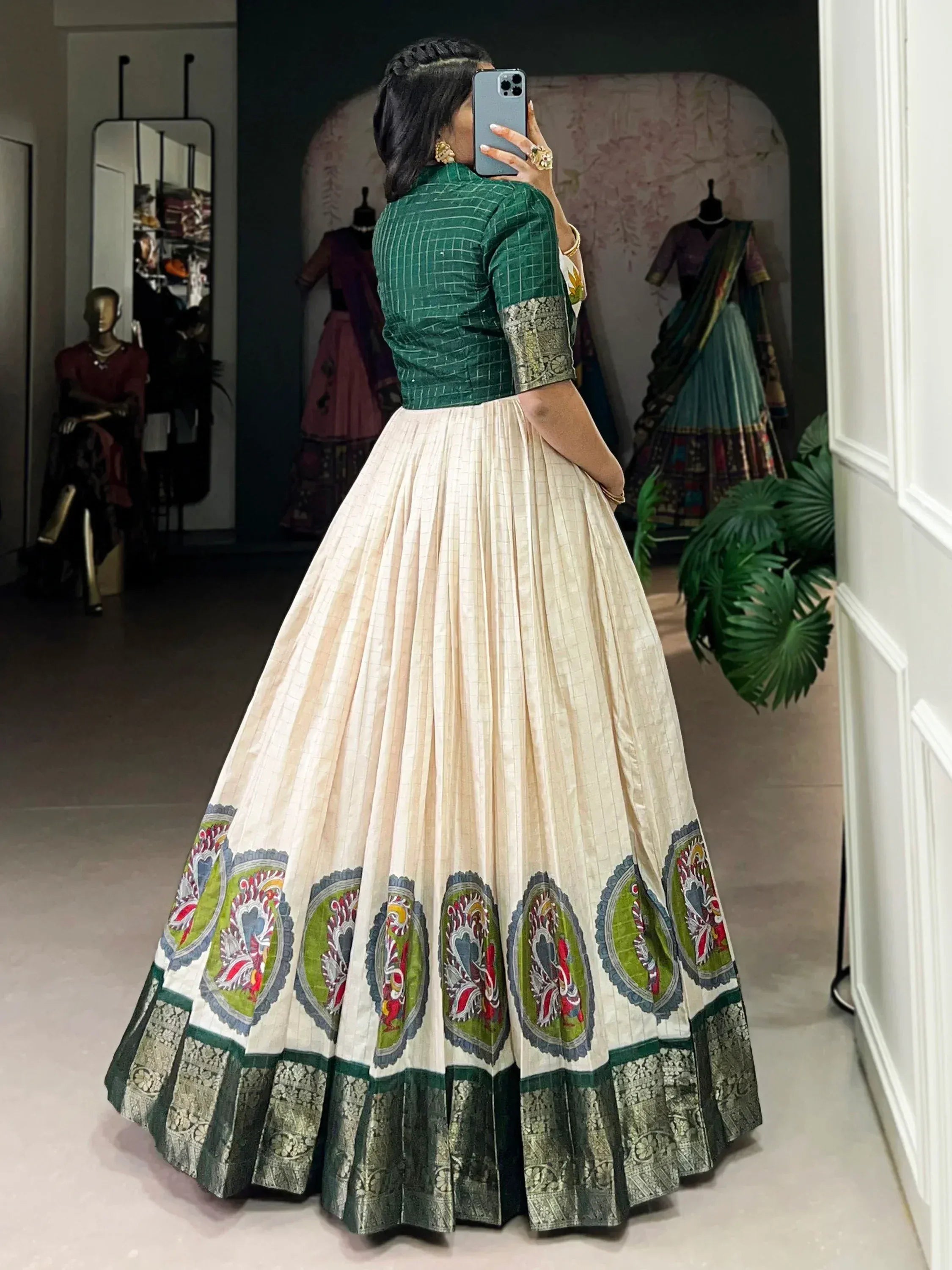Woman in green blouse and cream ethnic lehenga with traditional embroidery, indoor setting