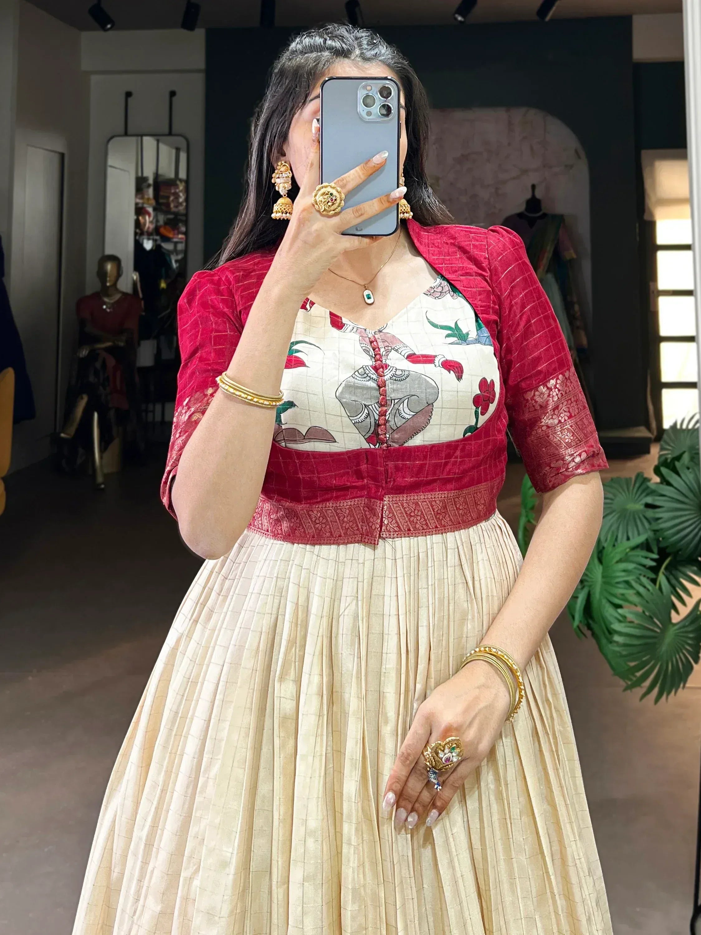 Woman in cream pleated skirt and red velvet jacket with floral print top, traditional Indian ethnic wear