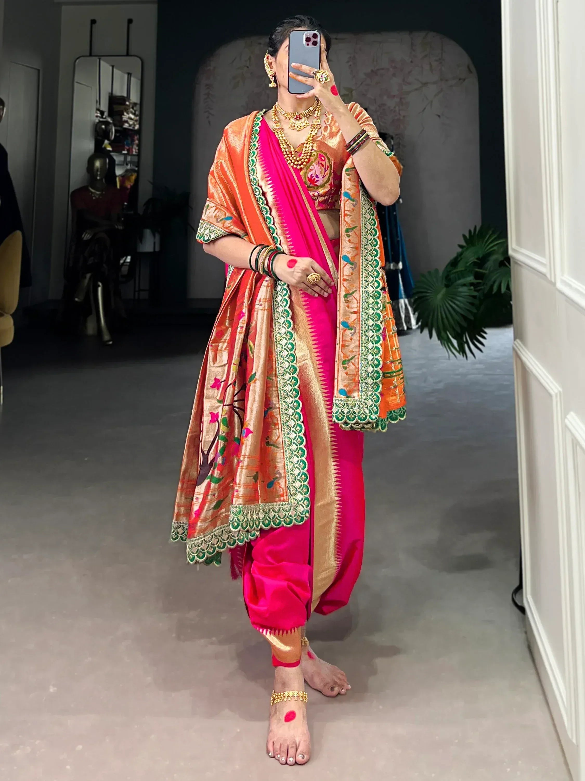 Vibrant pink and orange Indian ethnic saree with intricate green embroidery and gold jewelry