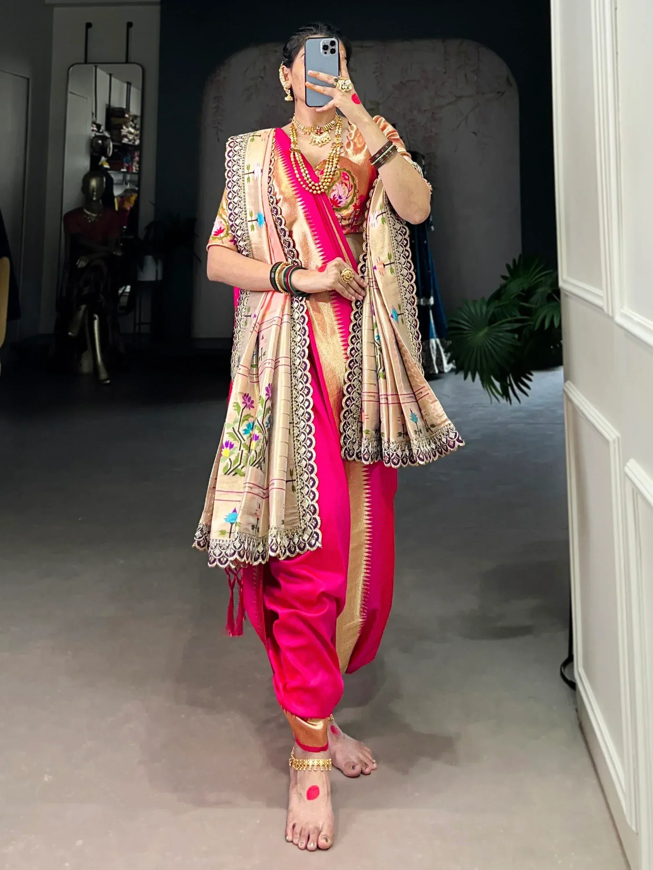 Vibrant pink Indian ethnic saree with floral embroidery and gold borders, paired with traditional jewelry.