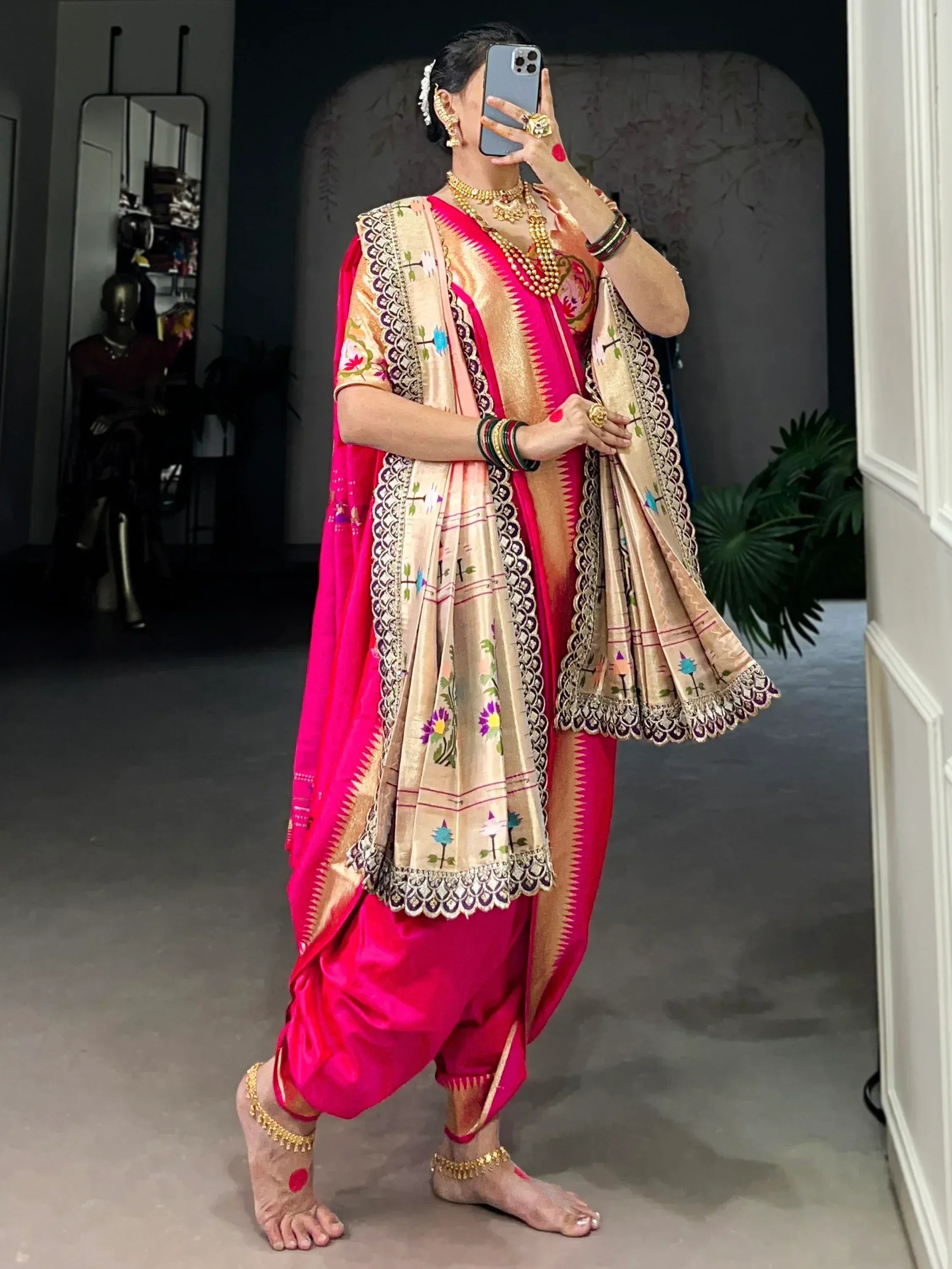 Vibrant pink and gold embroidered saree with floral motifs, paired with traditional jewelry and barefoot styling.
