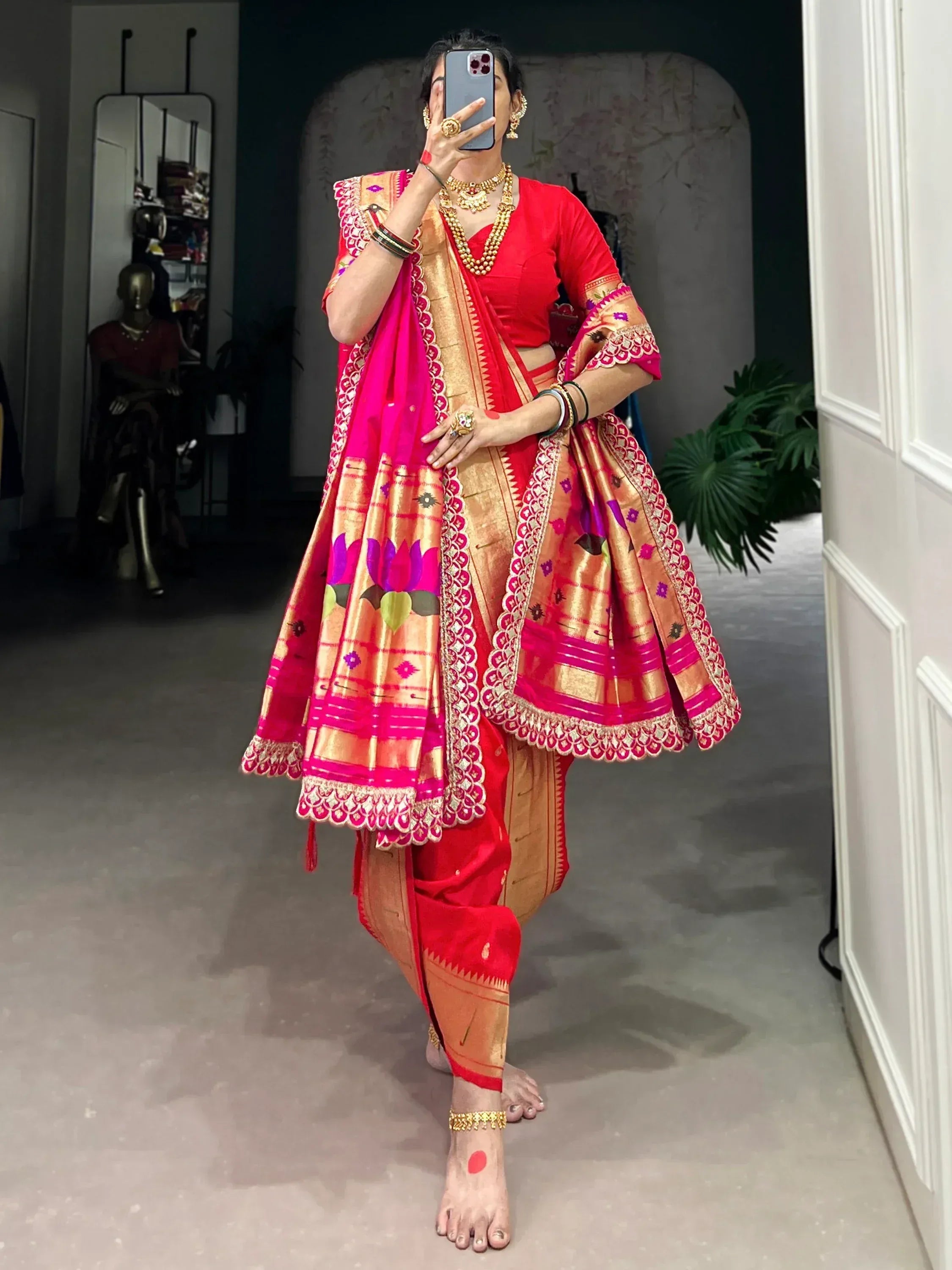 Vibrant red and gold ethnic saree with floral motifs and intricate borders, paired with traditional jewelry.