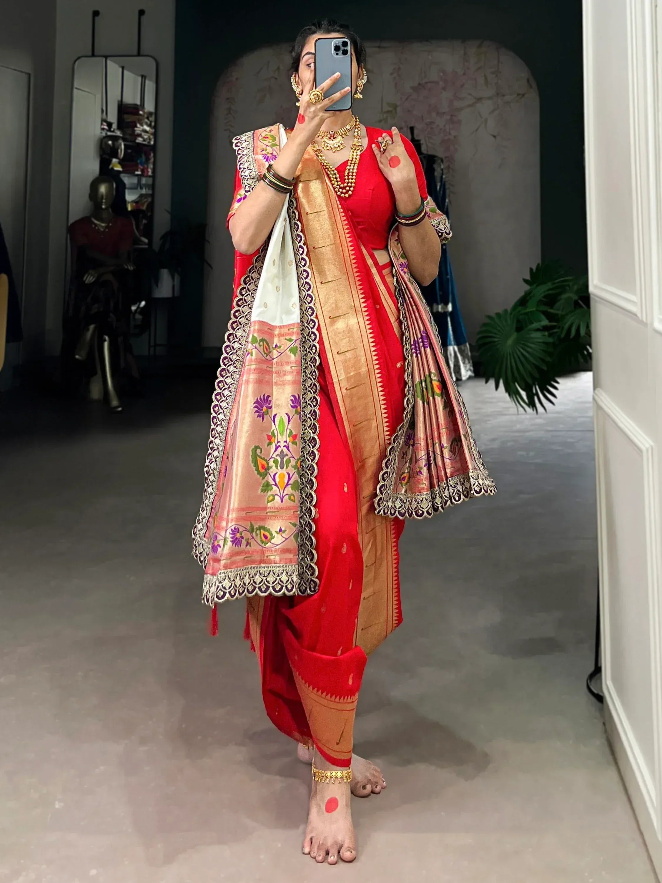 Red ethnic saree with gold border and floral embroidery, paired with traditional jewelry
