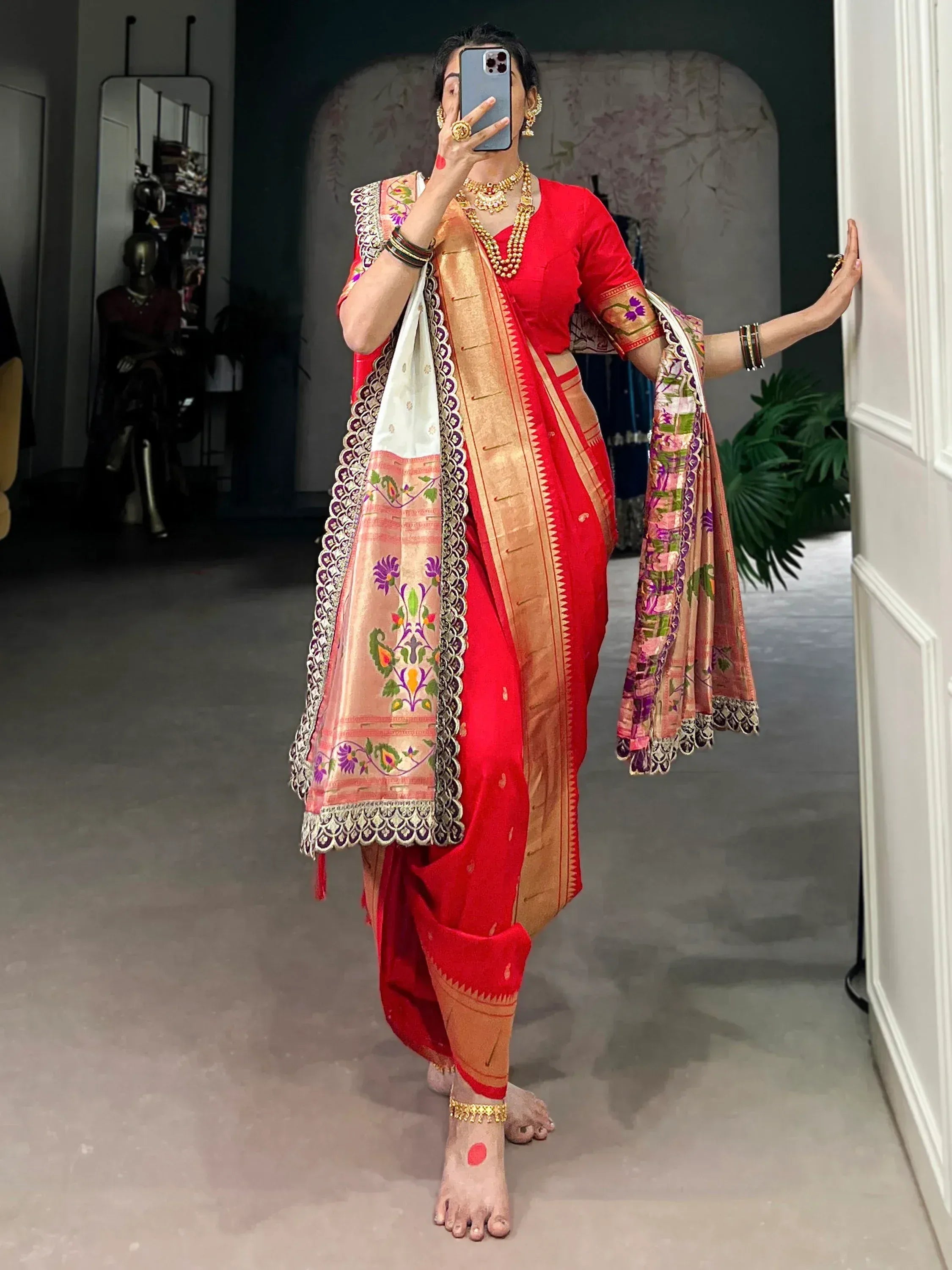 Red ethnic saree with floral embroidery and gold border, paired with traditional jewelry