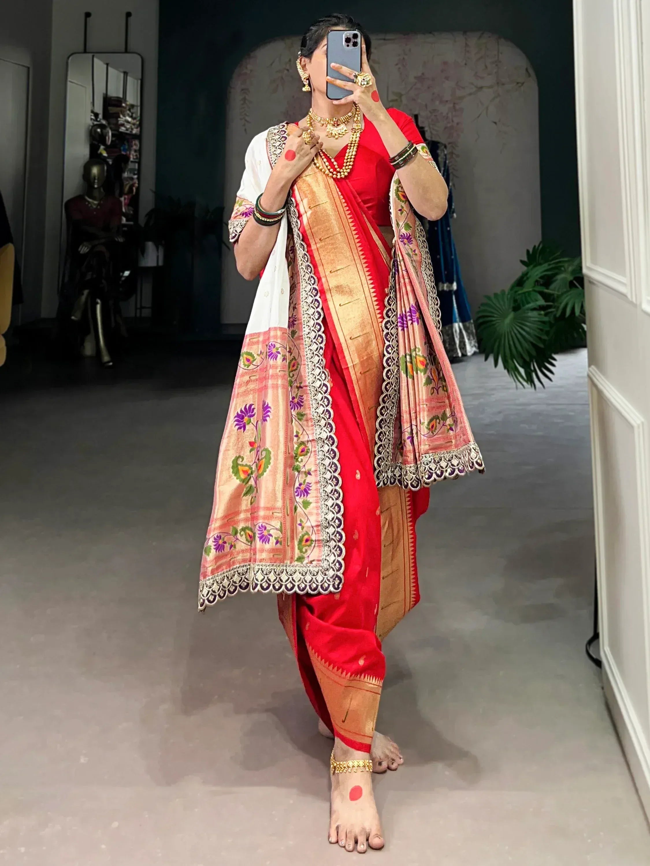 Red ethnic saree with floral embroidery and gold border, paired with traditional jewelry