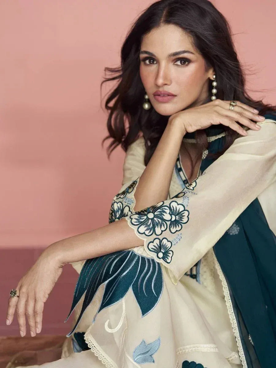Woman in cream and teal floral embroidered ethnic gown with pearl earrings