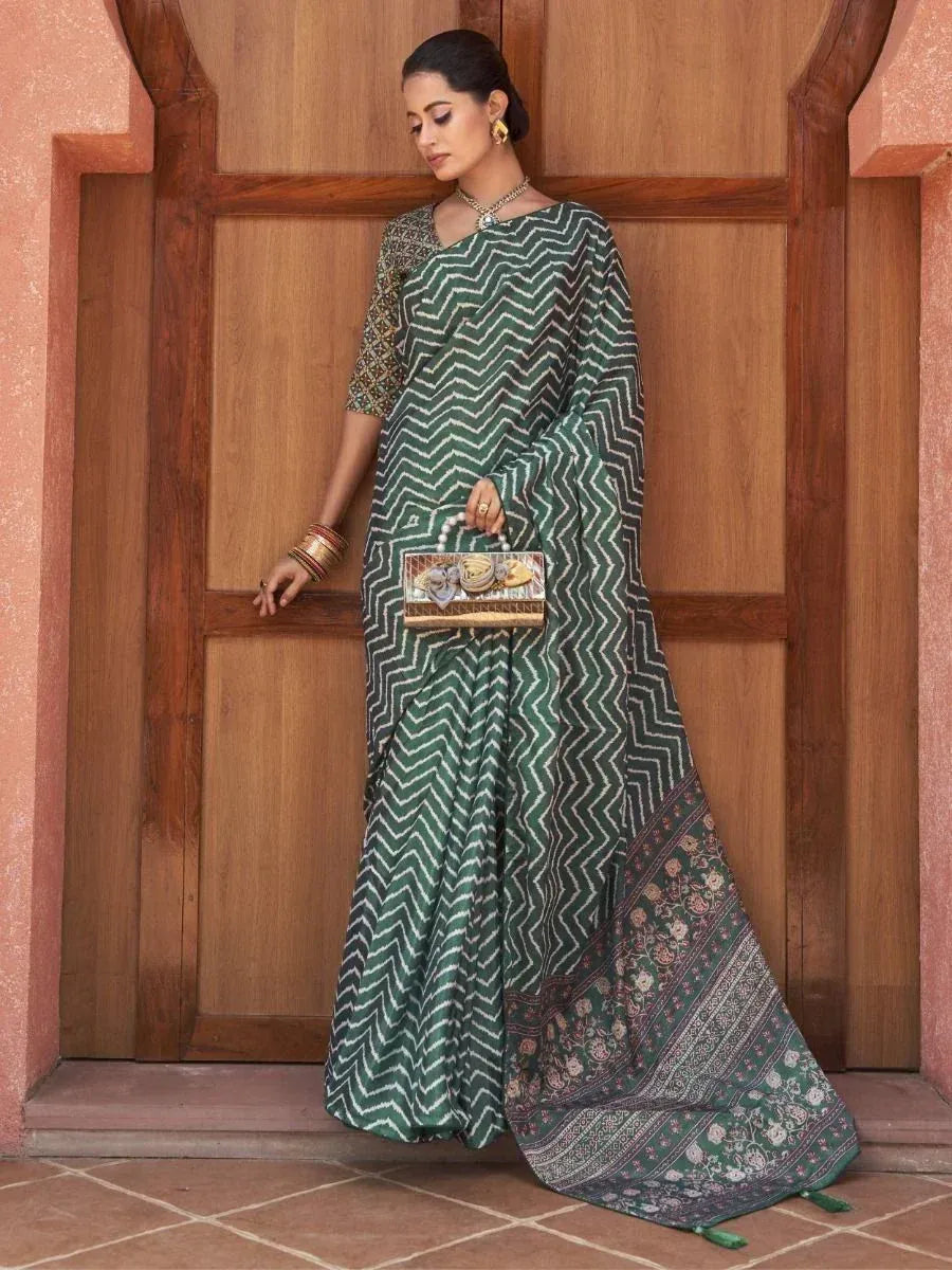 Green zigzag patterned saree with floral border, styled with gold jewelry and clutch for ethnic occasions