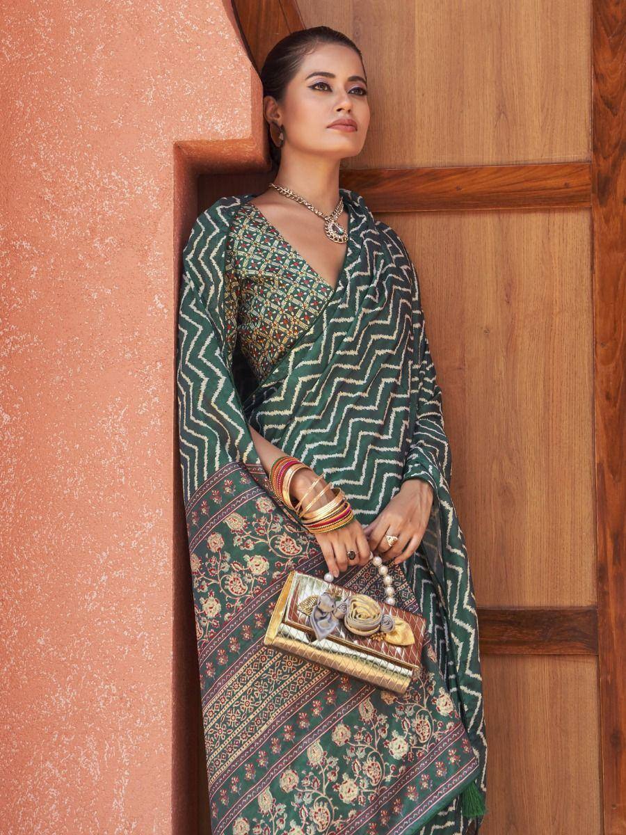 Green printed saree with geometric and floral patterns, paired with gold jewelry and clutch, perfect for ethnic occasions.