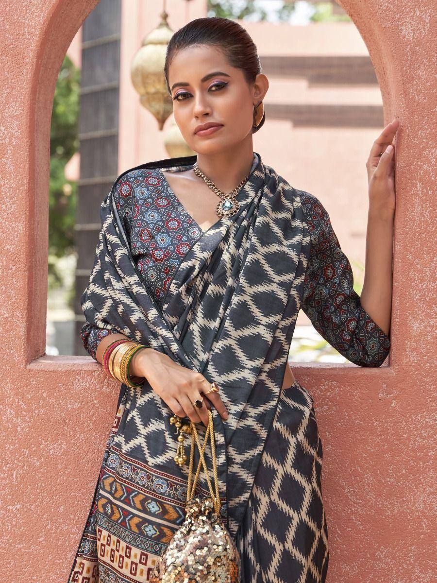 Woman in printed ethnic saree with geometric patterns, gold jewelry, and sequin bag, styled for Indian occasions