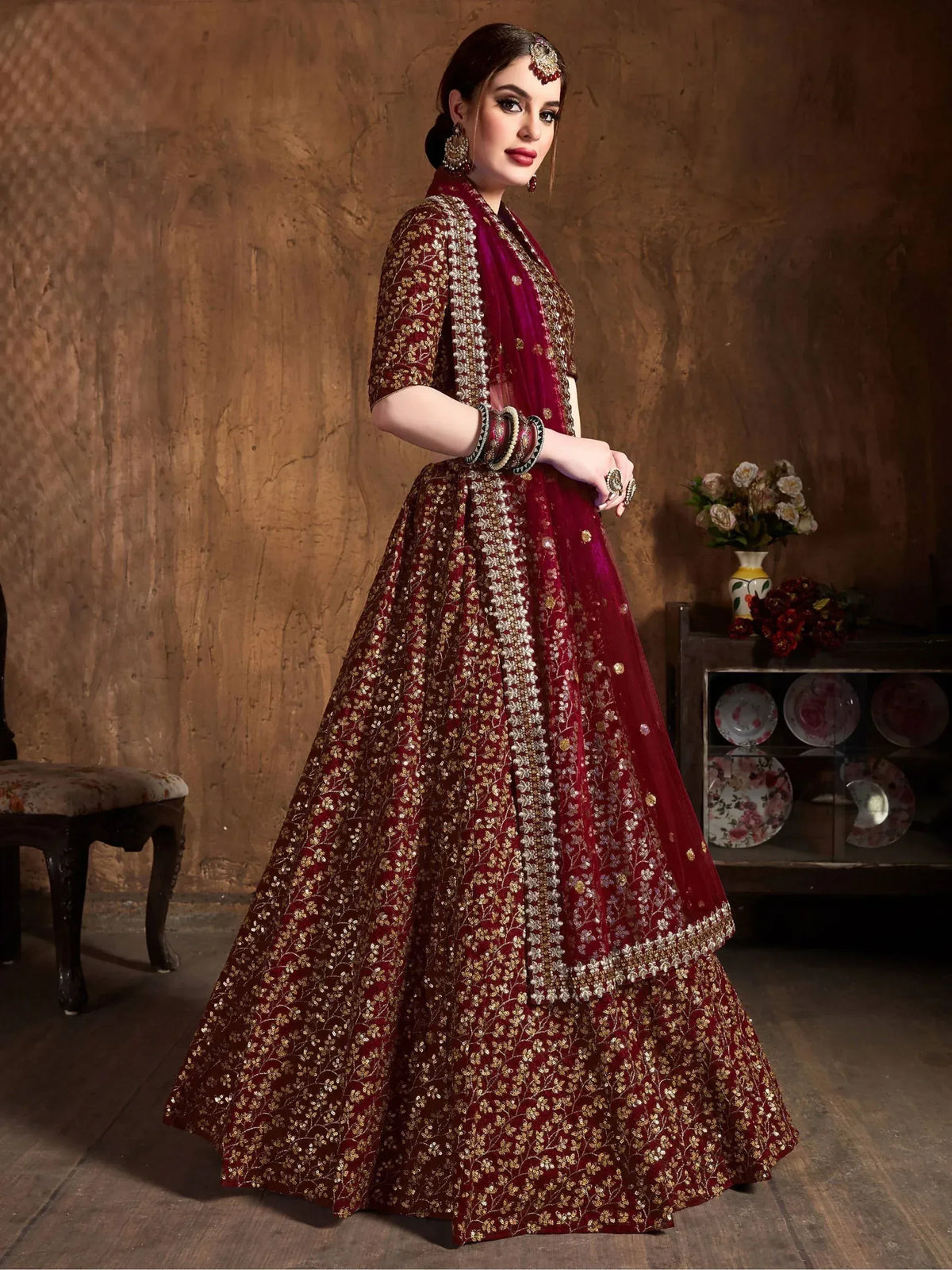 Maroon designer lehenga choli with gold floral embroidery and sequins, perfect for weddings and festive occasions.