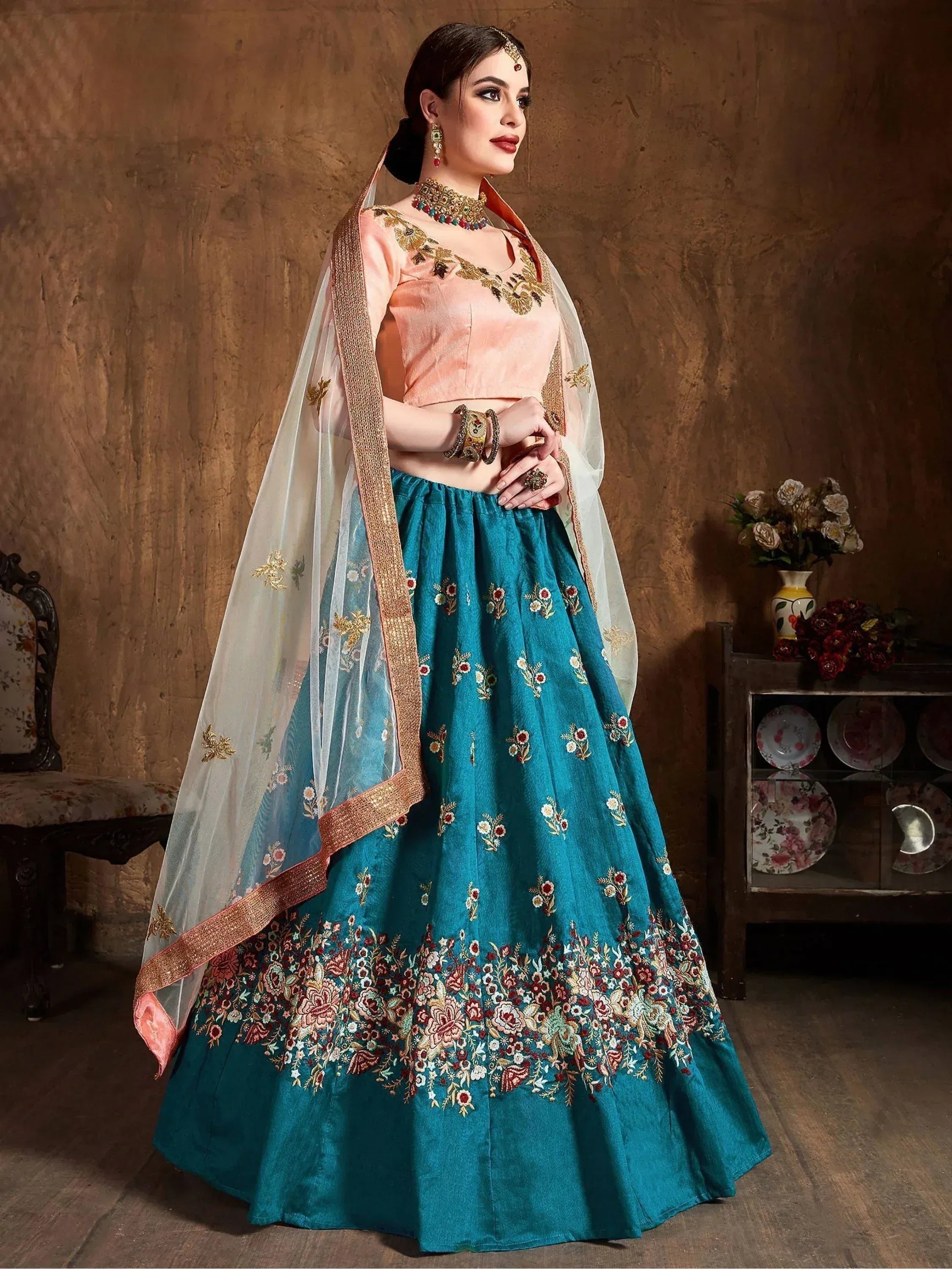 Teal and peach embroidered lehenga choli with floral detailing and sheer dupatta, perfect for Indian weddings and festivals.