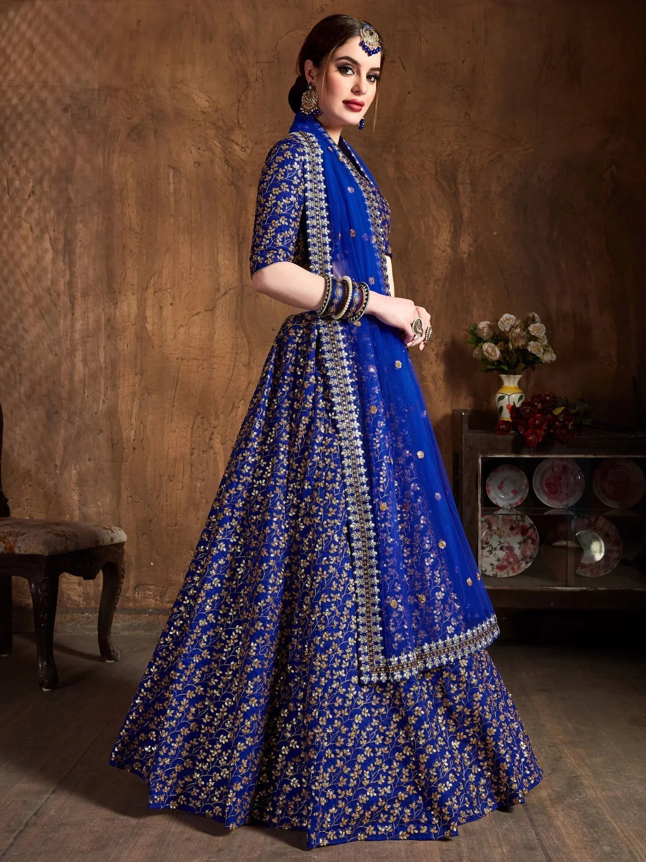 Royal blue designer lehenga choli with gold floral embroidery, perfect for Indian weddings and festive occasions.