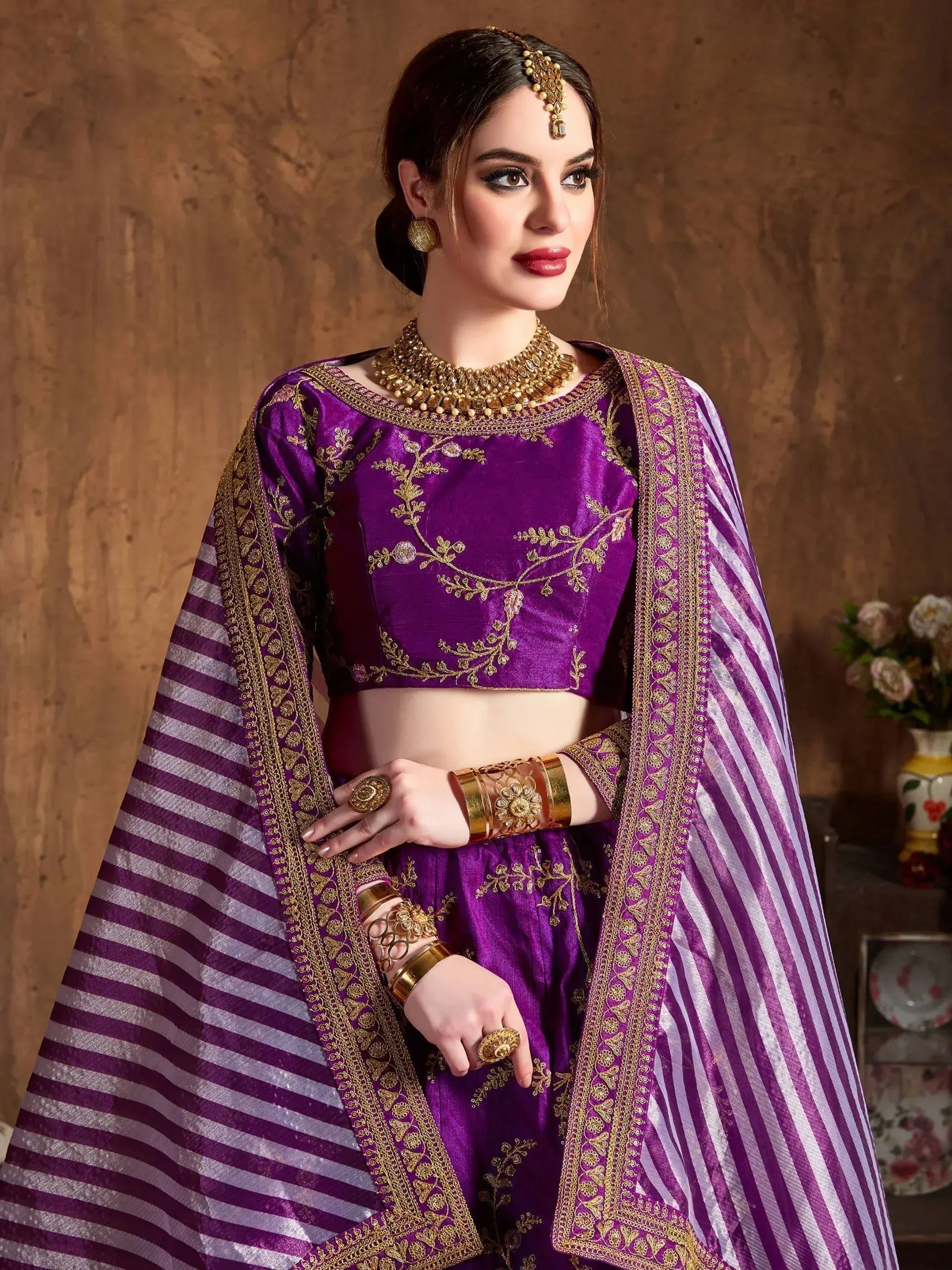 Purple embroidered lehenga choli with gold detailing and striped dupatta, perfect for Indian ethnic occasions.
