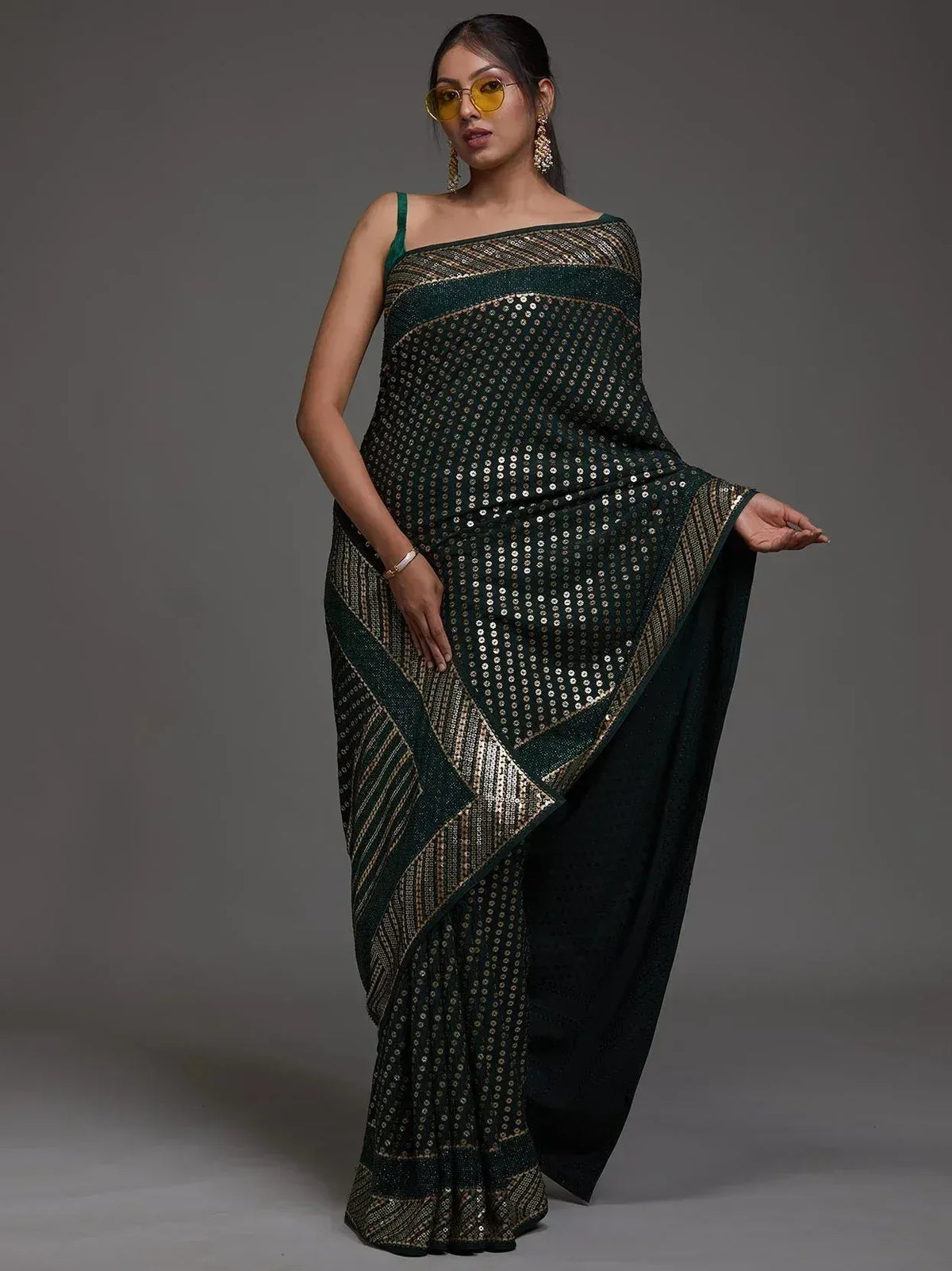 Elegant dark green sequin saree with gold geometric patterns, styled for festive occasions.