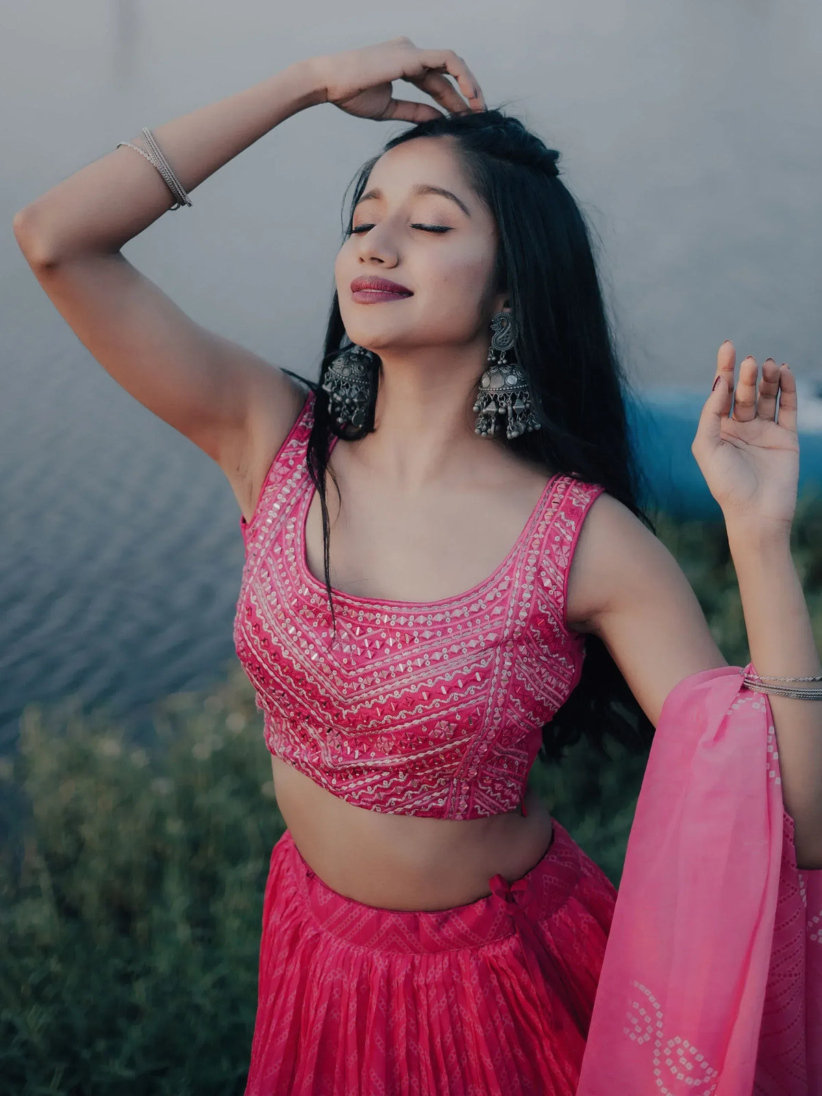 Woman in pink embroidered lehenga choli with mirror work, traditional Indian ethnic wear, jhumka earrings