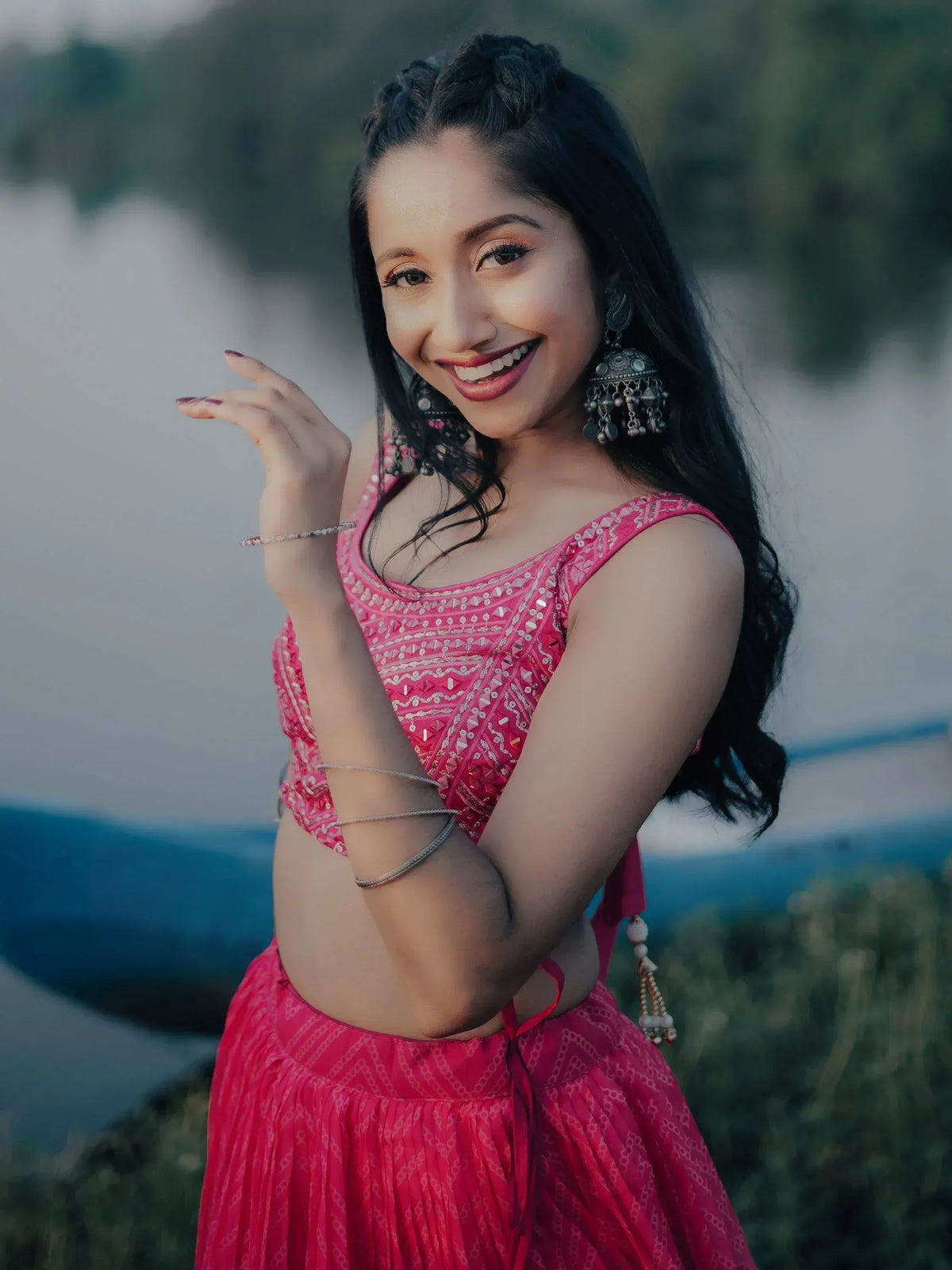 Woman in pink embroidered lehenga choli with jhumka earrings, smiling outdoors