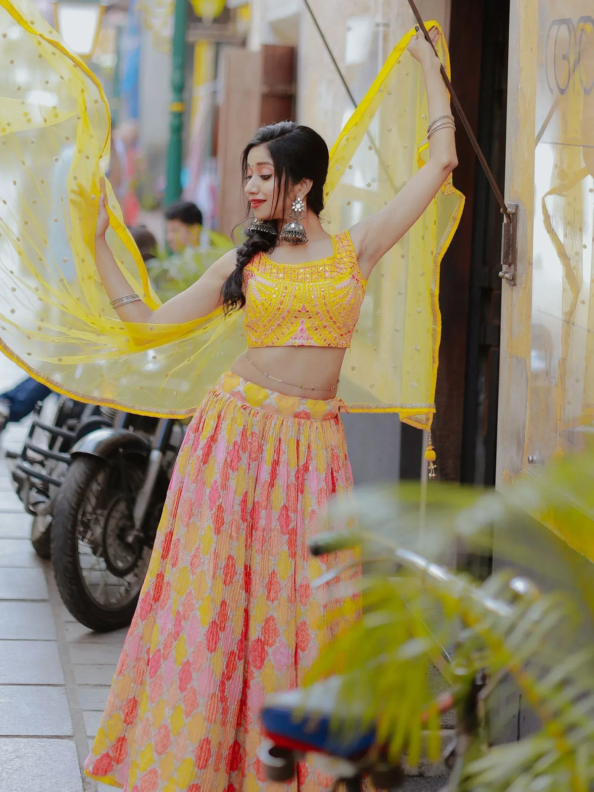 Woman in vibrant yellow and pink lehenga choli with sheer dupatta, showcasing Indian ethnic wear
