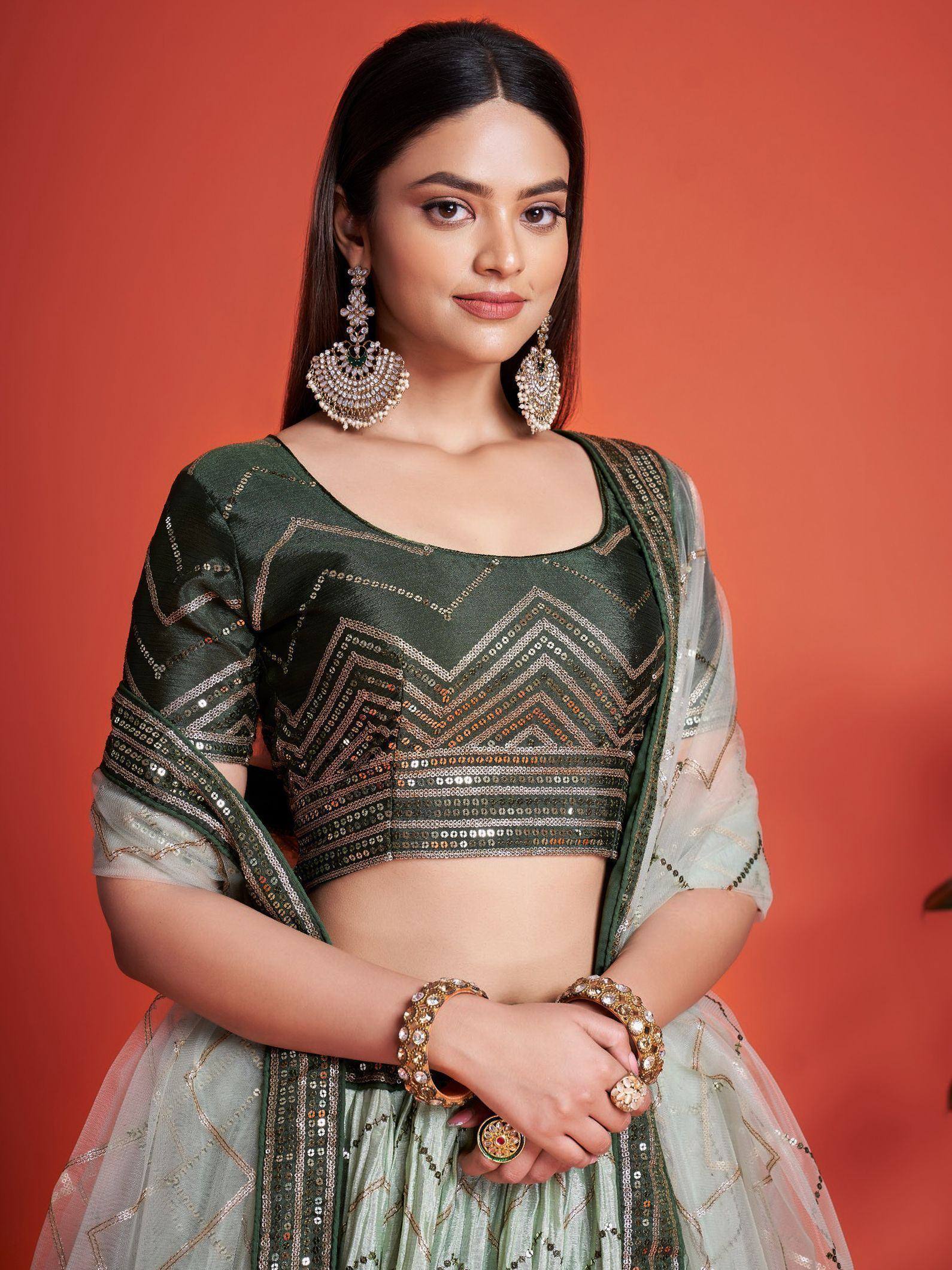 Green sequin lehenga choli with chevron embroidery, sheer dupatta, and statement jewelry for Indian ethnic wear