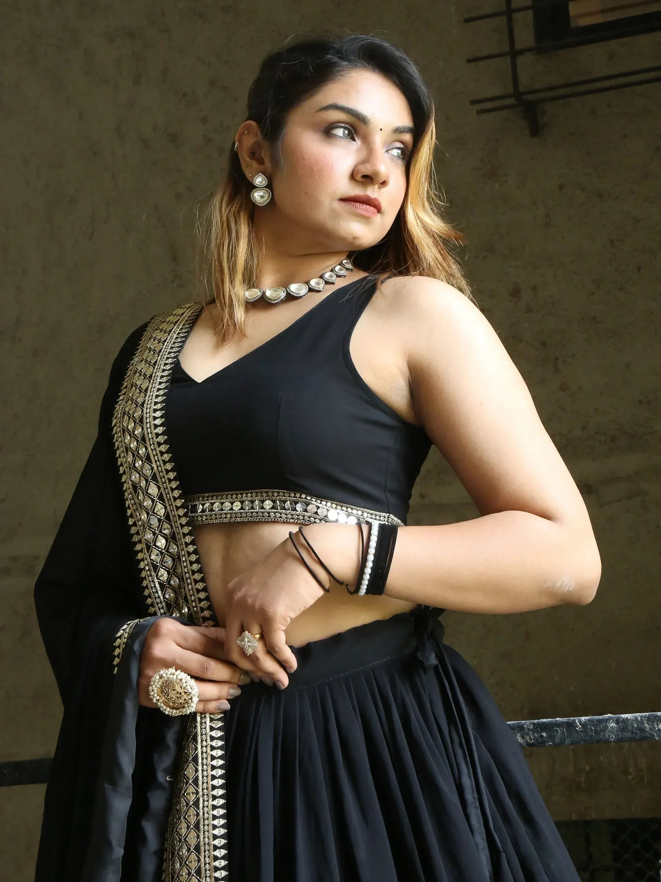 Black designer lehenga choli with gold embroidery and mirror work, paired with statement jewelry