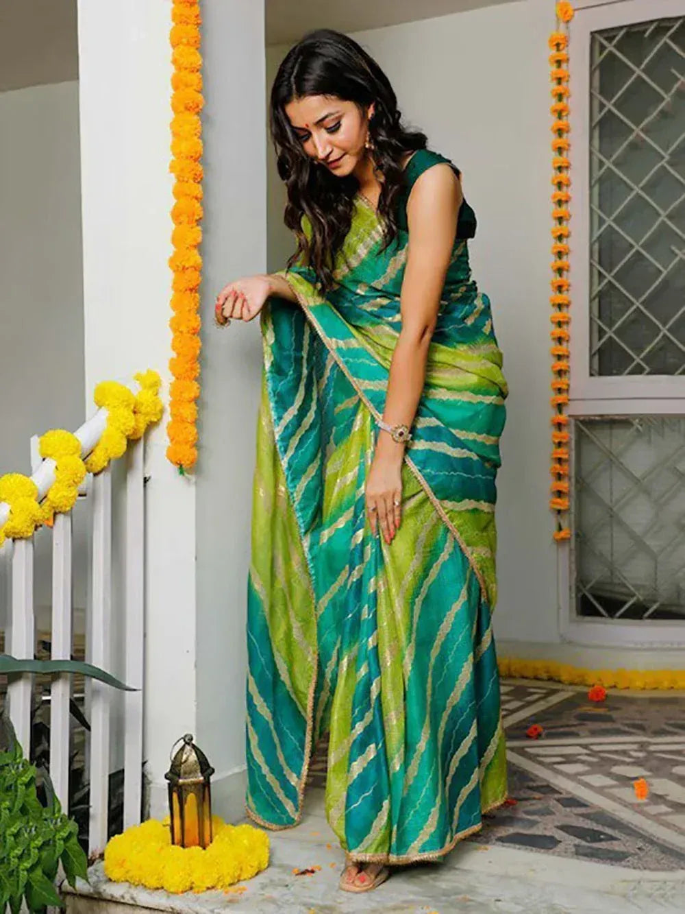 Woman in green and teal striped saree with gold trim, festive marigold decor, Indian ethnic wear