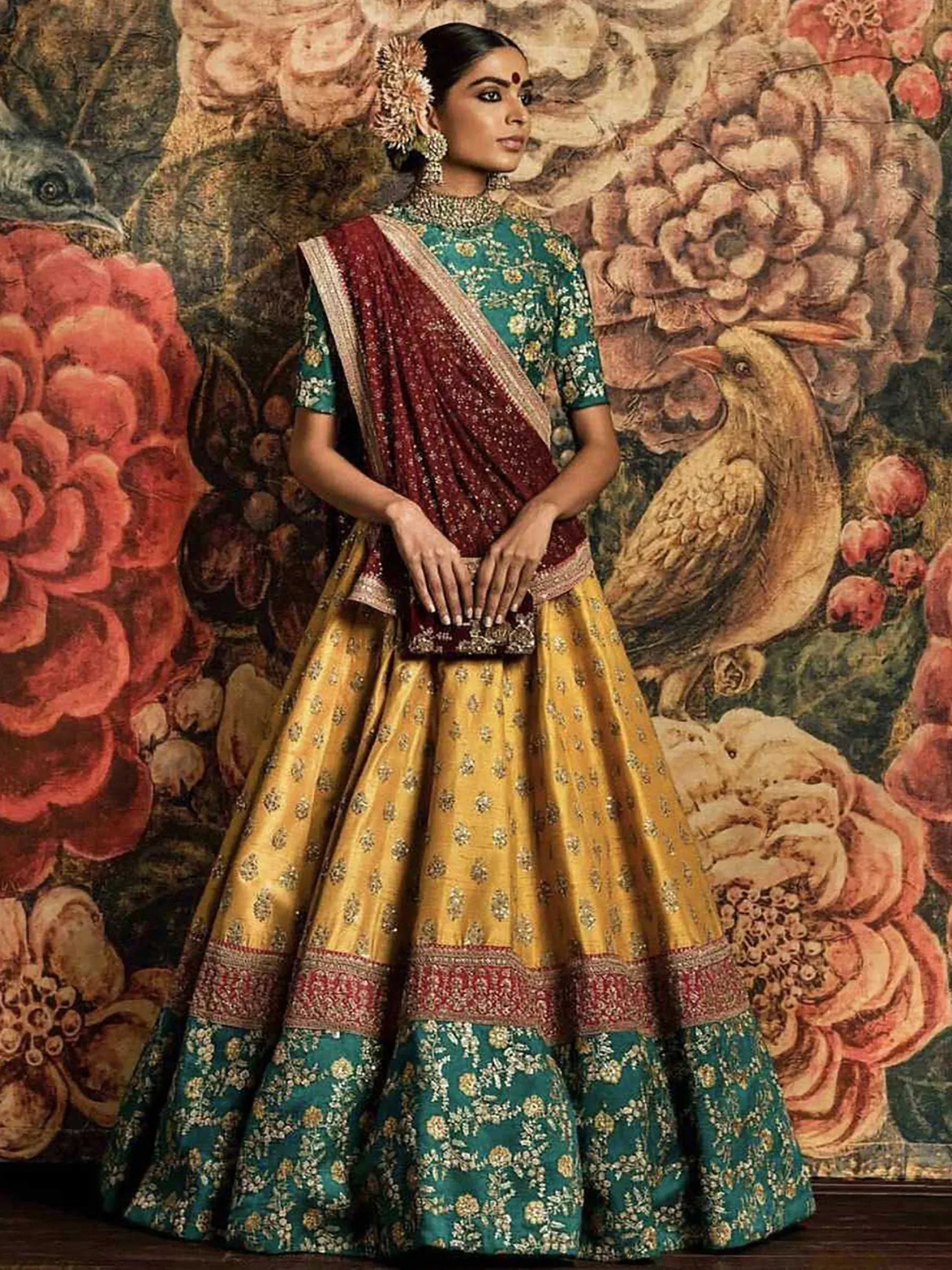 Elegant Indian lehenga choli with teal blouse, gold skirt, and maroon dupatta, perfect for weddings and festive occasions.