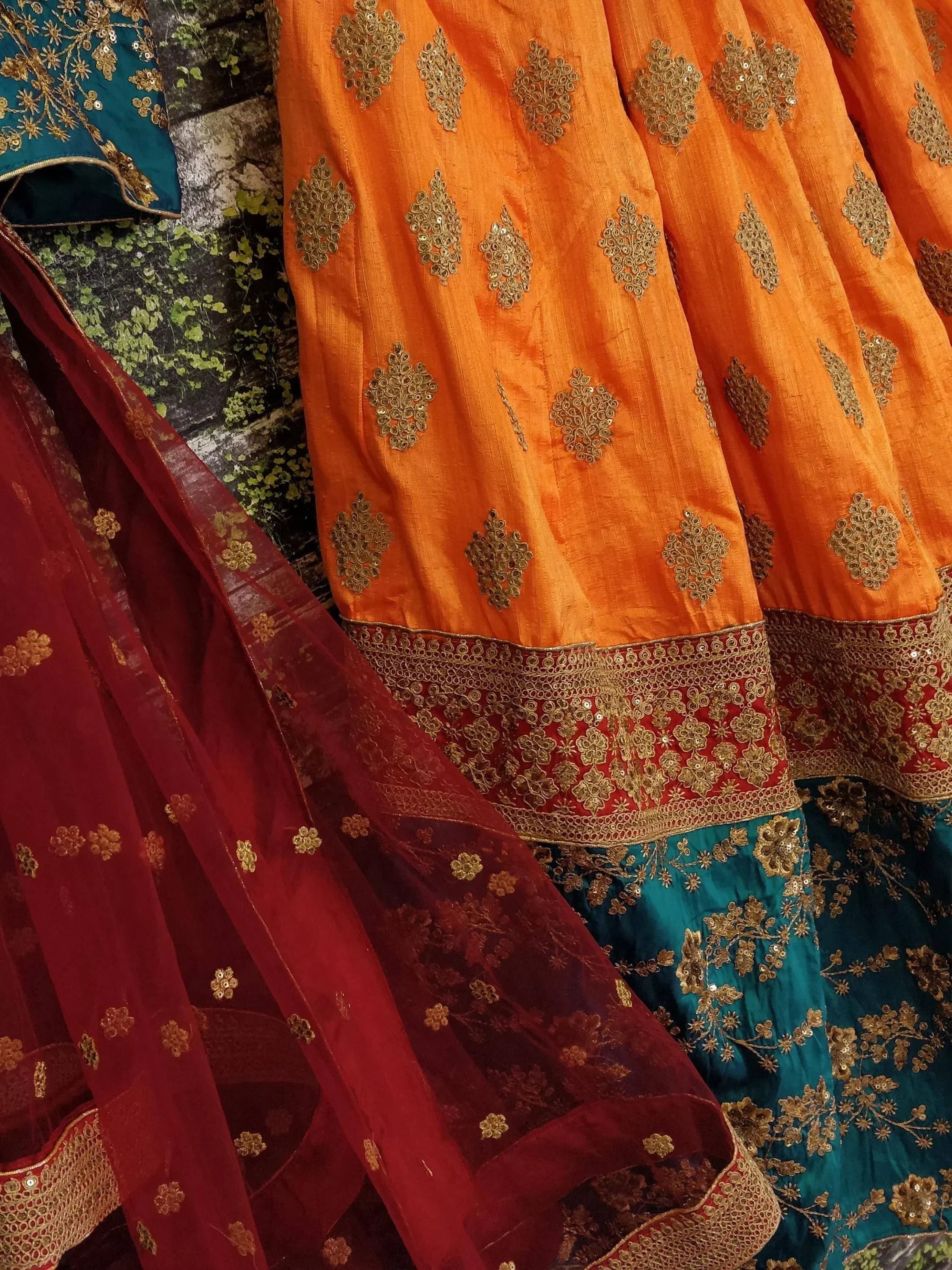 Orange and teal Indian lehenga with gold embroidery and red dupatta, ethnic wear for festive occasions