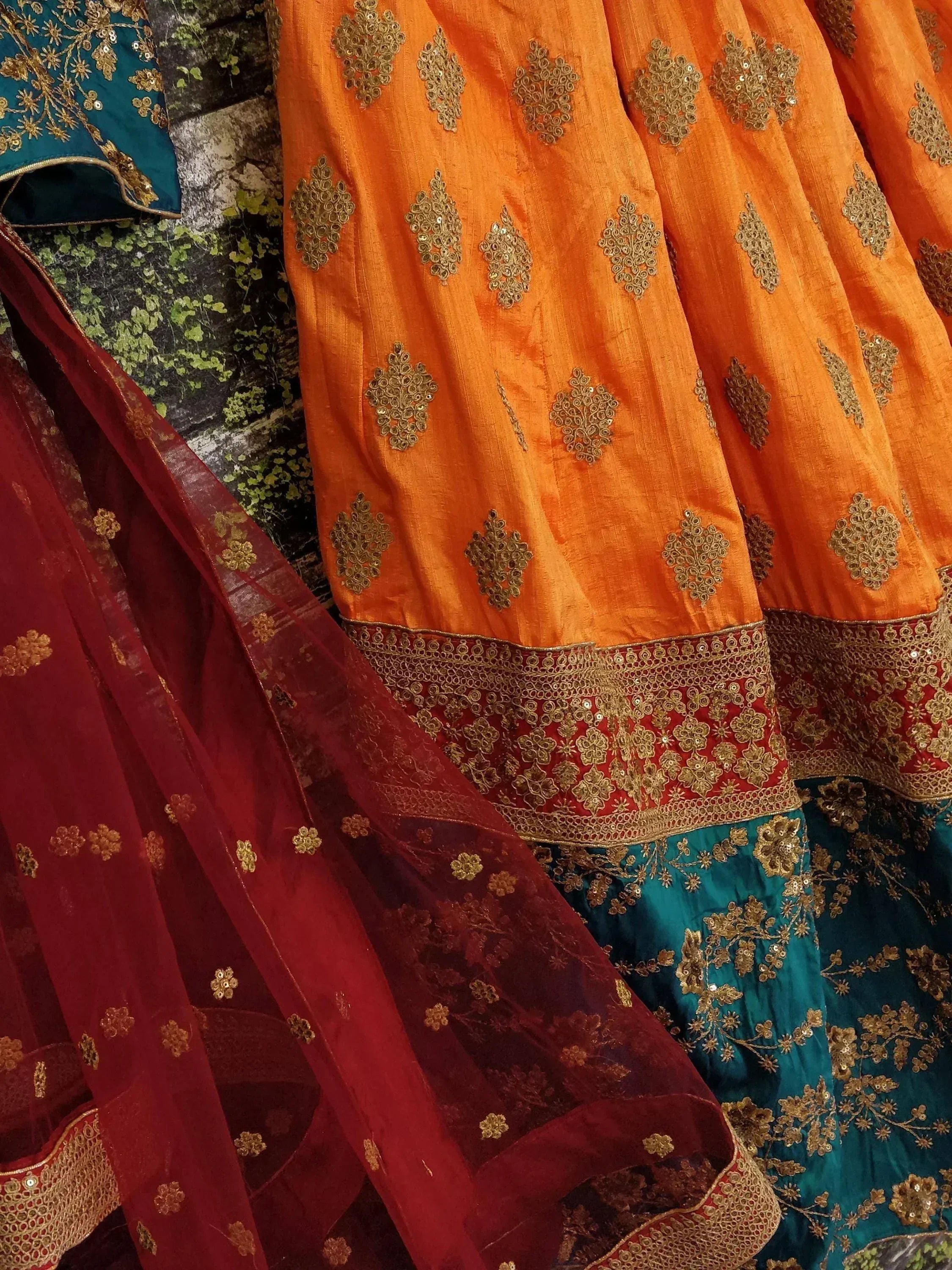 Orange and teal Indian lehenga with gold embroidery and red dupatta, ethnic wear for festive occasions