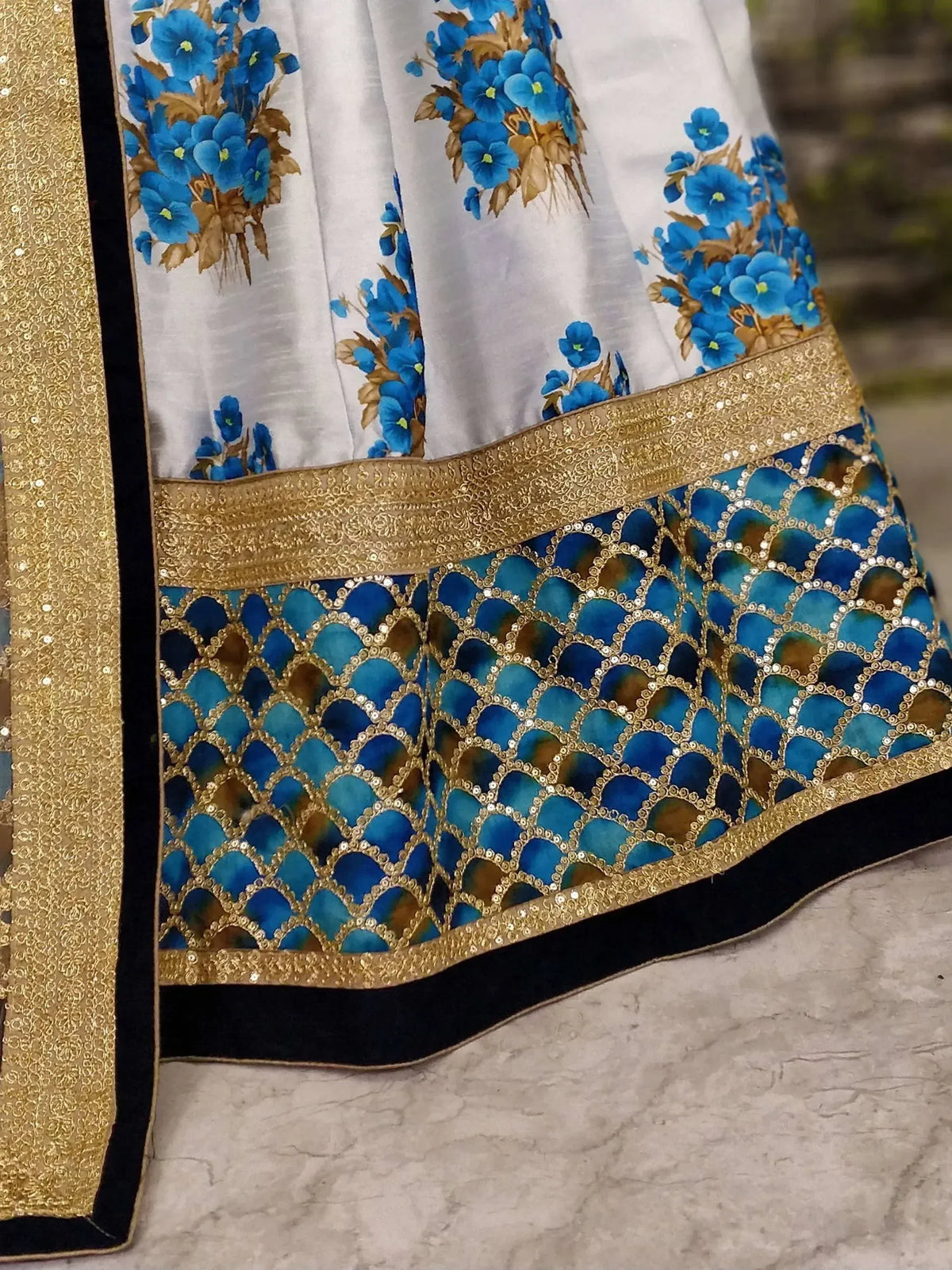 White and blue floral lehenga with gold sequin border and peacock feather pattern