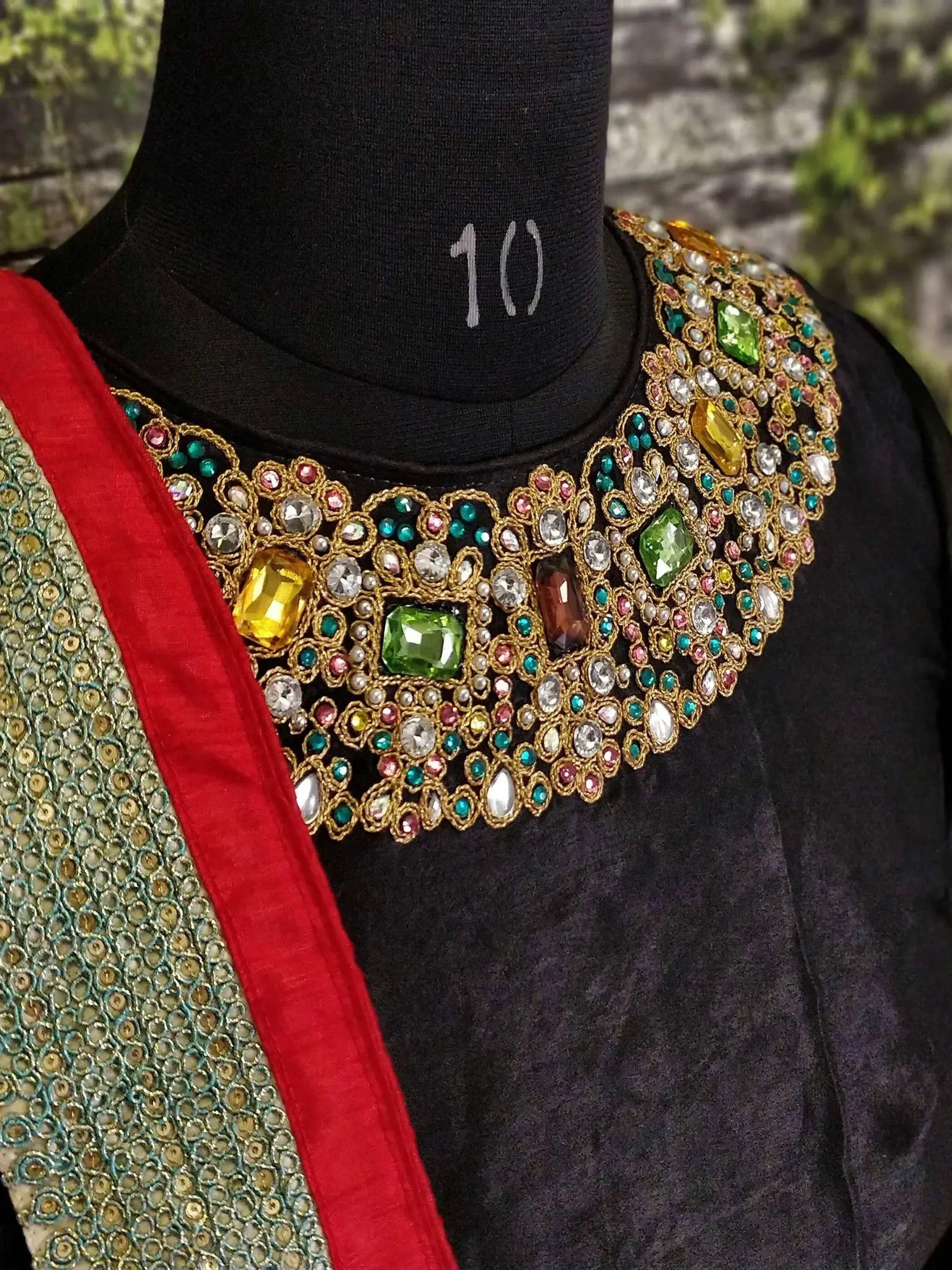 Black ethnic blouse with heavy gemstone neckline, paired with sequined saree, perfect for Indian weddings or festive occasions.