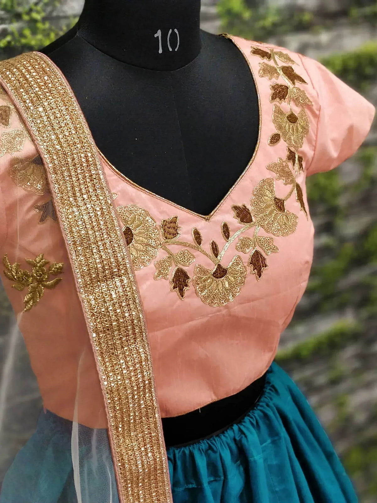 Pink embroidered blouse with gold floral work, paired with teal skirt, ethnic Indian wear
