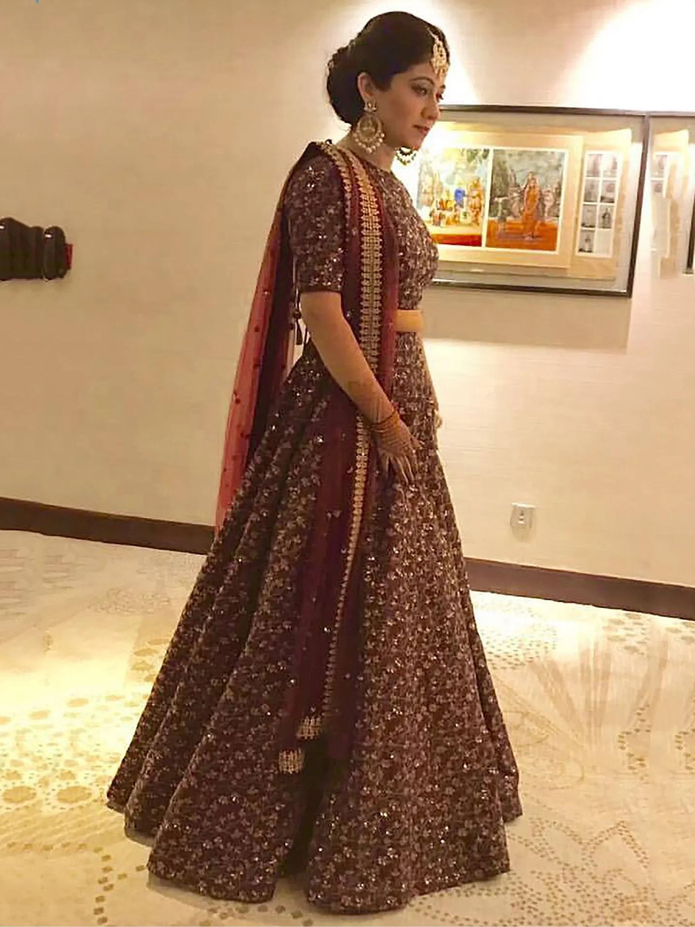 Elegant maroon lehenga choli with gold embroidery, perfect for Indian weddings and festive occasions.