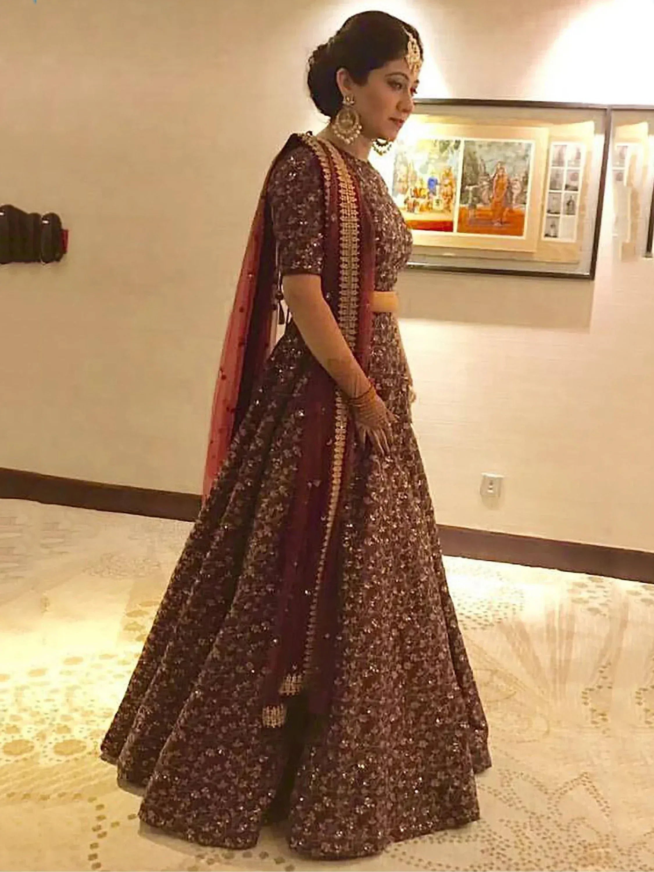 Elegant maroon lehenga choli with gold embroidery, perfect for Indian weddings and festive occasions.
