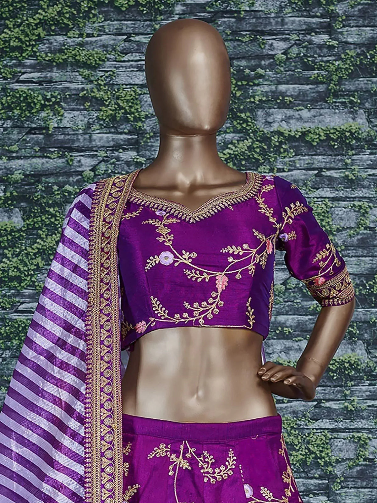 Purple embroidered lehenga choli with gold floral work and striped dupatta, displayed on mannequin