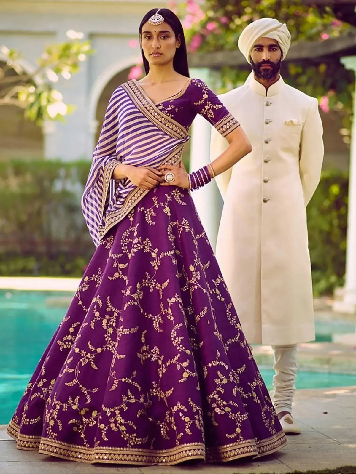 Purple embroidered lehenga choli with striped dupatta, paired with cream sherwani for Indian wedding wear