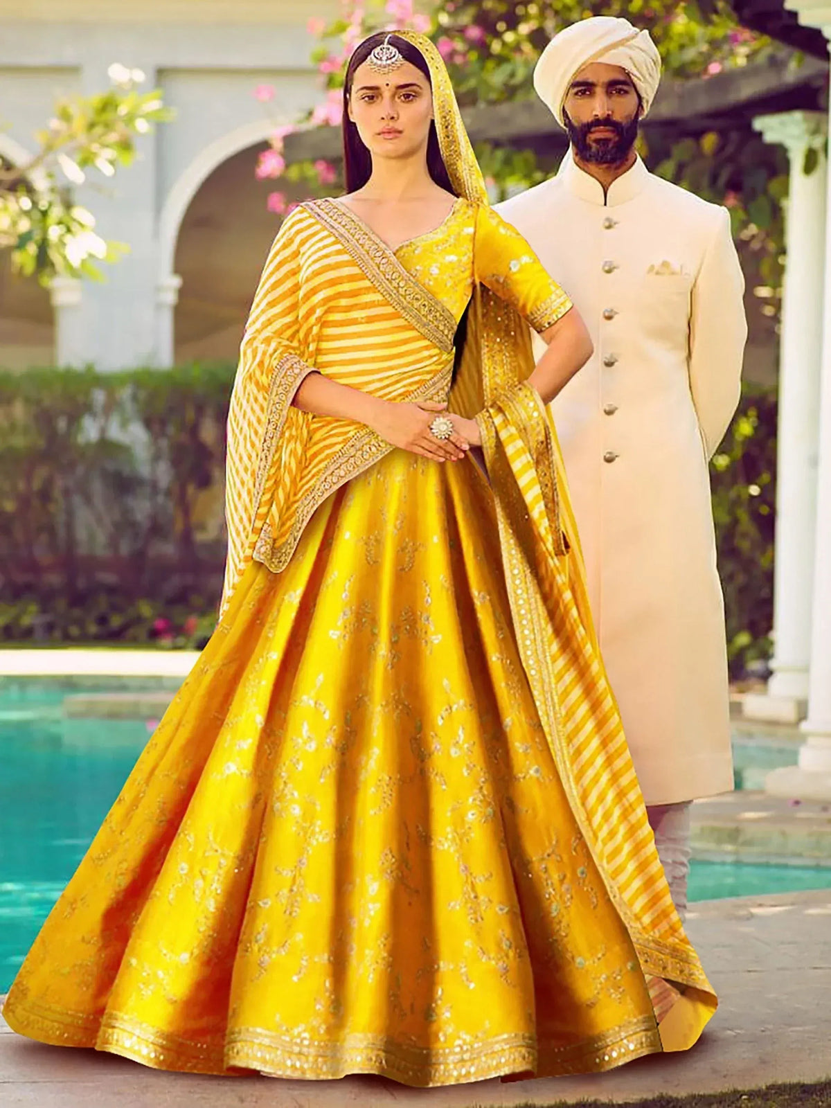 Yellow embroidered lehenga choli with striped dupatta, paired with cream sherwani for Indian wedding wear