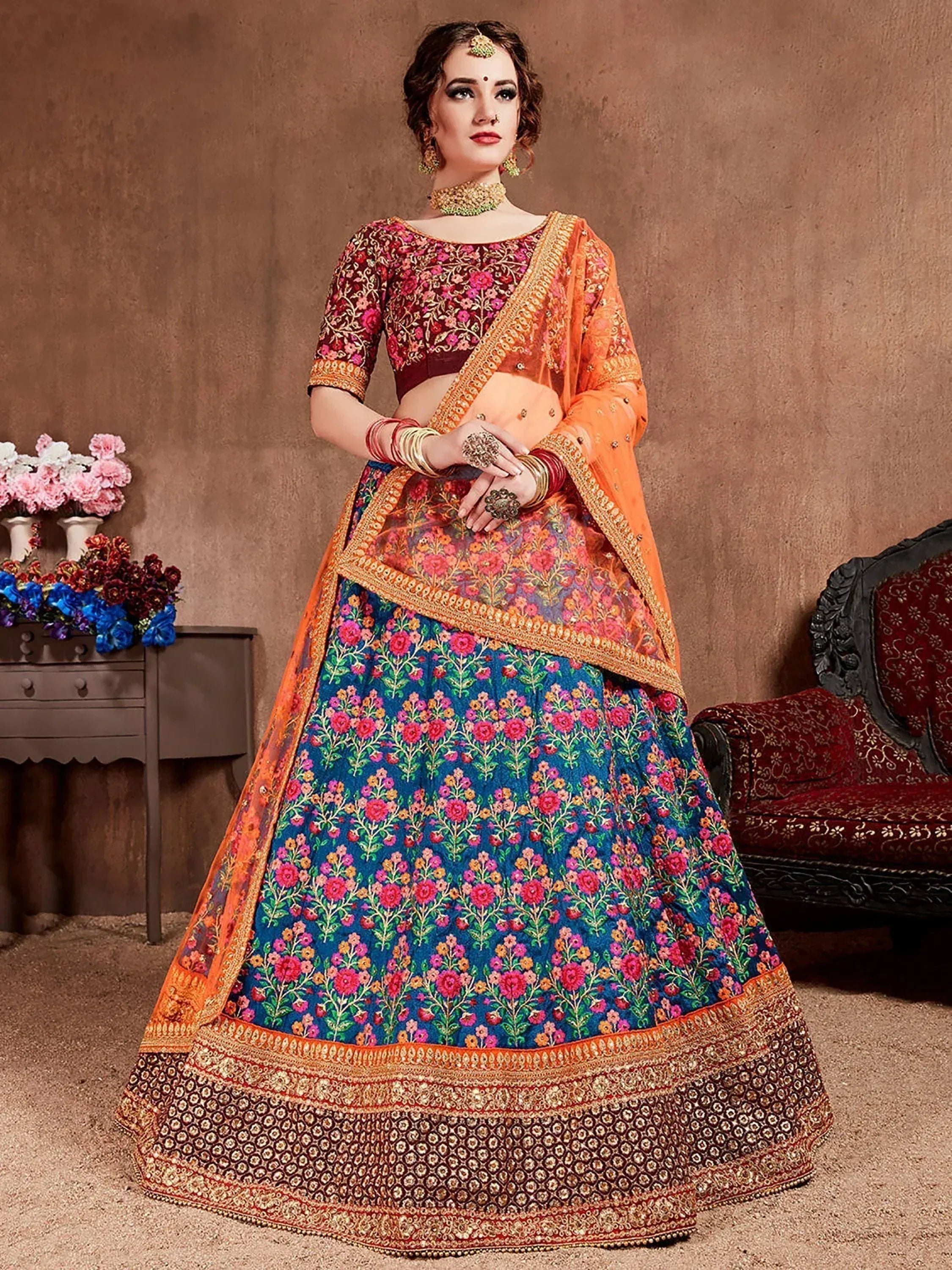 Designer lehenga choli with floral embroidery, orange dupatta, and ethnic jewelry for Indian weddings