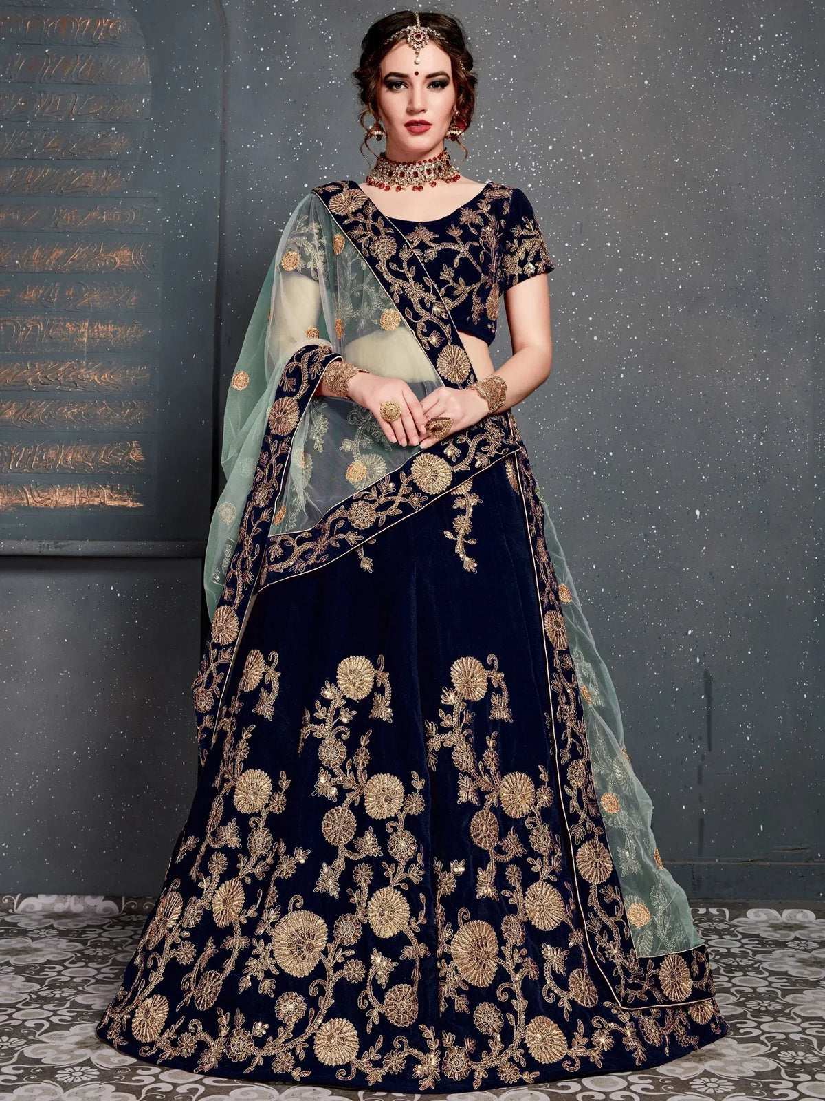 Navy blue velvet lehenga choli with gold floral embroidery and sheer mint dupatta, perfect for Indian weddings.