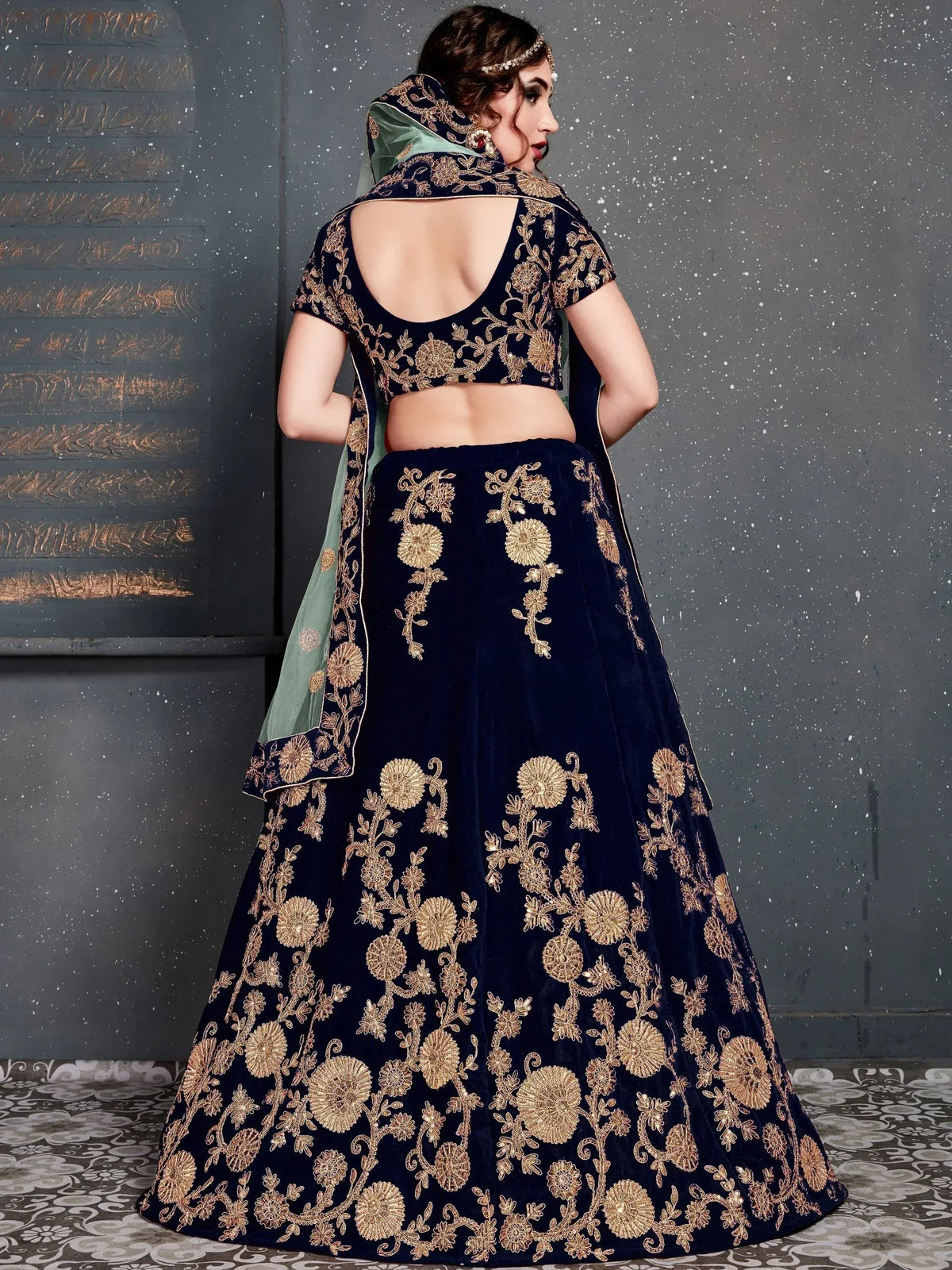 Navy blue velvet lehenga choli with gold floral embroidery and green dupatta, back view