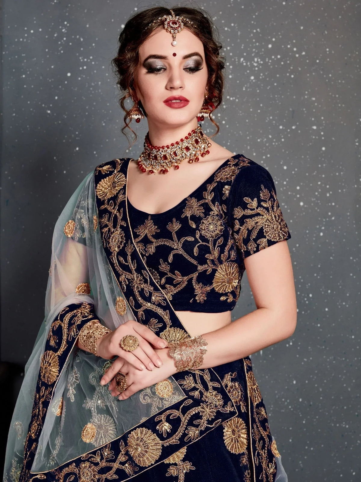 Navy blue velvet lehenga choli with gold floral embroidery, sheer dupatta, and traditional Indian jewelry